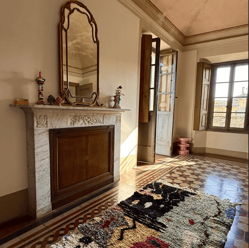 Salone d'epoca con camino in marmo, pavimento a scacchi e tappeto marocchino boucherouite
