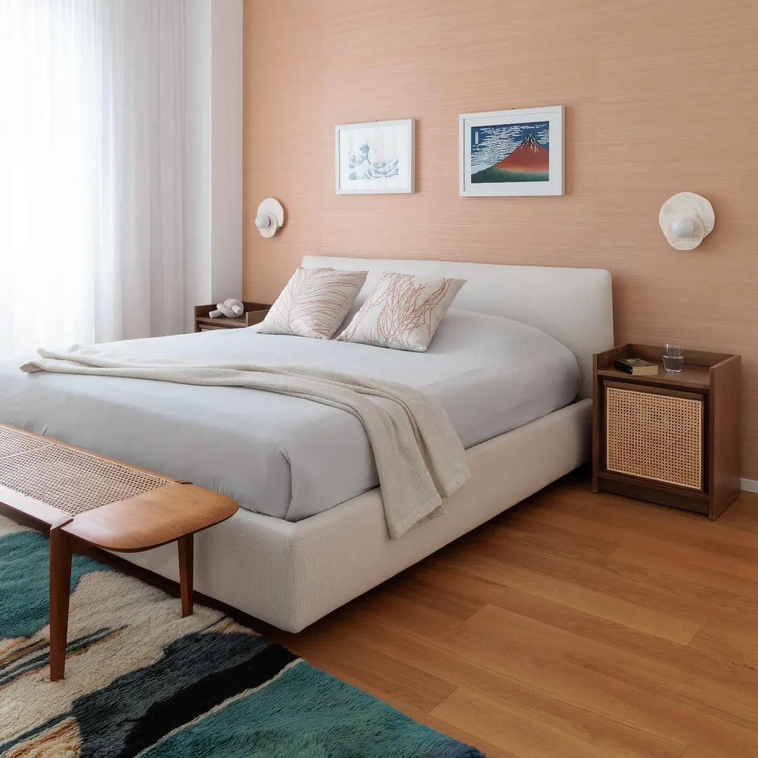 Chambre au mur vieux rose, lit blanc, banc en bois et tapis marocain vert et bleu