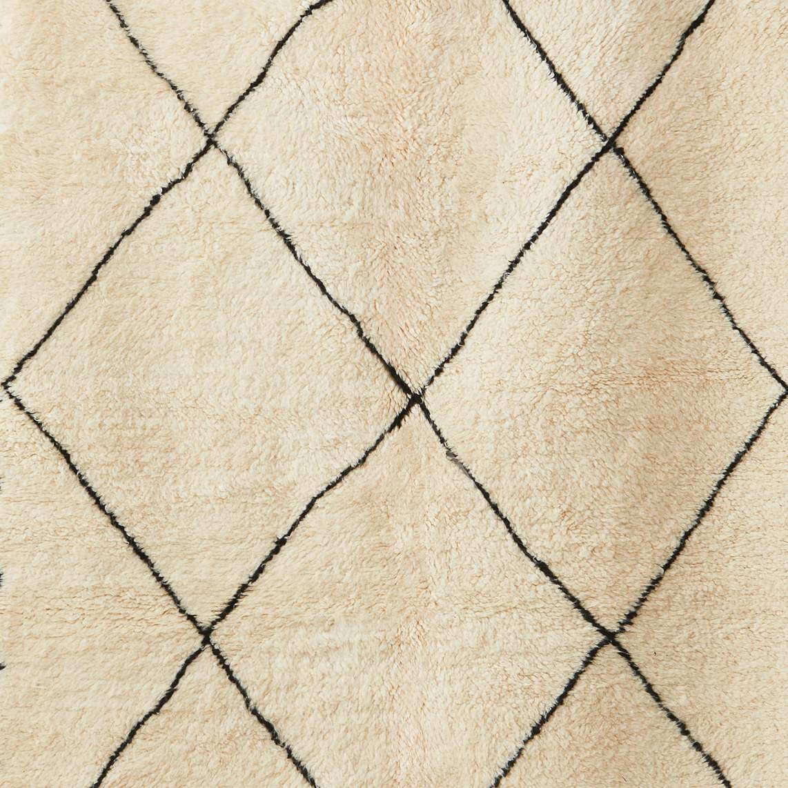 Détail du motif à losanges noirs d'un tapis Beni Ouarain en laine blanche