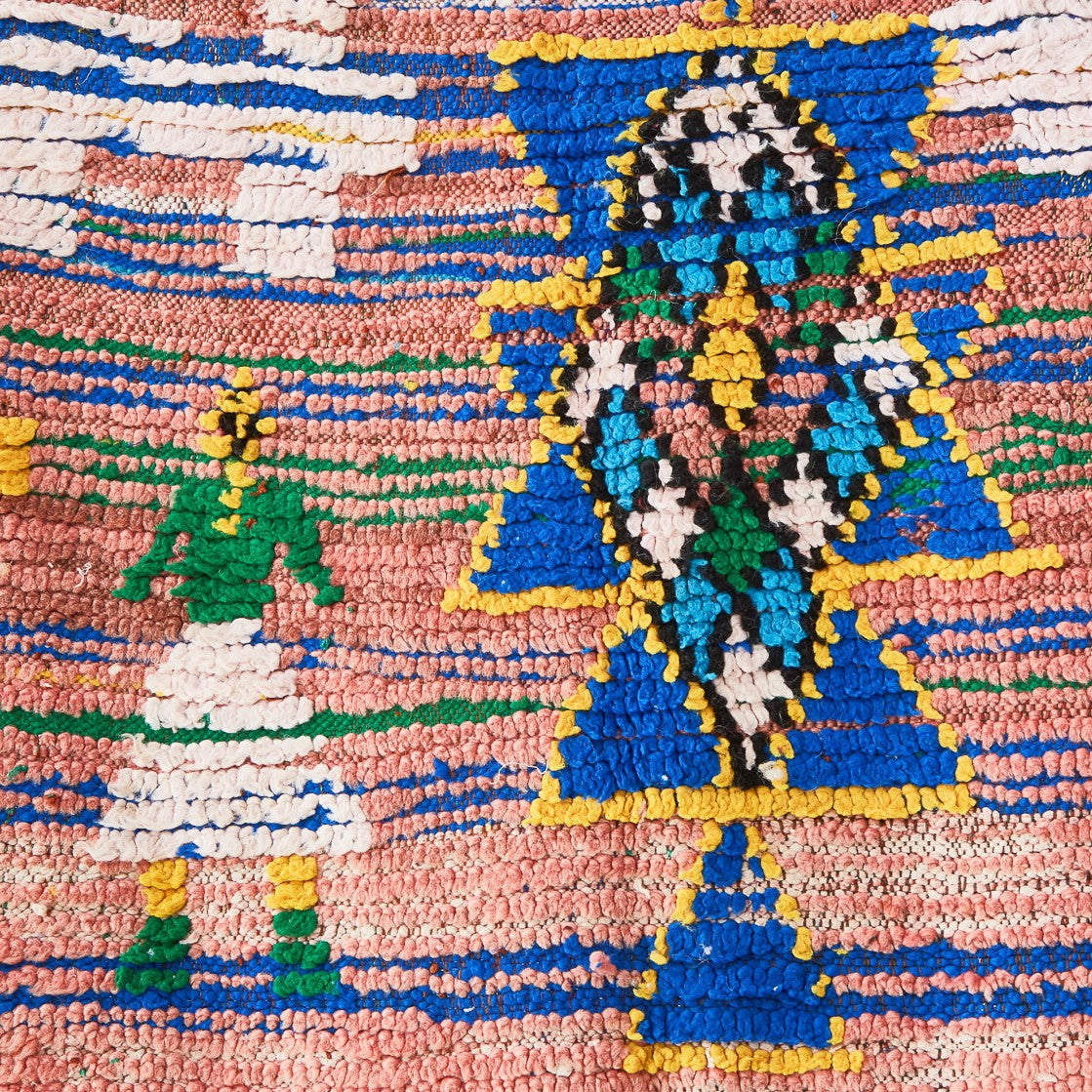 Détail d'un tapis Azilal patiné avec un symbole amazigh bleu et une figure féminine