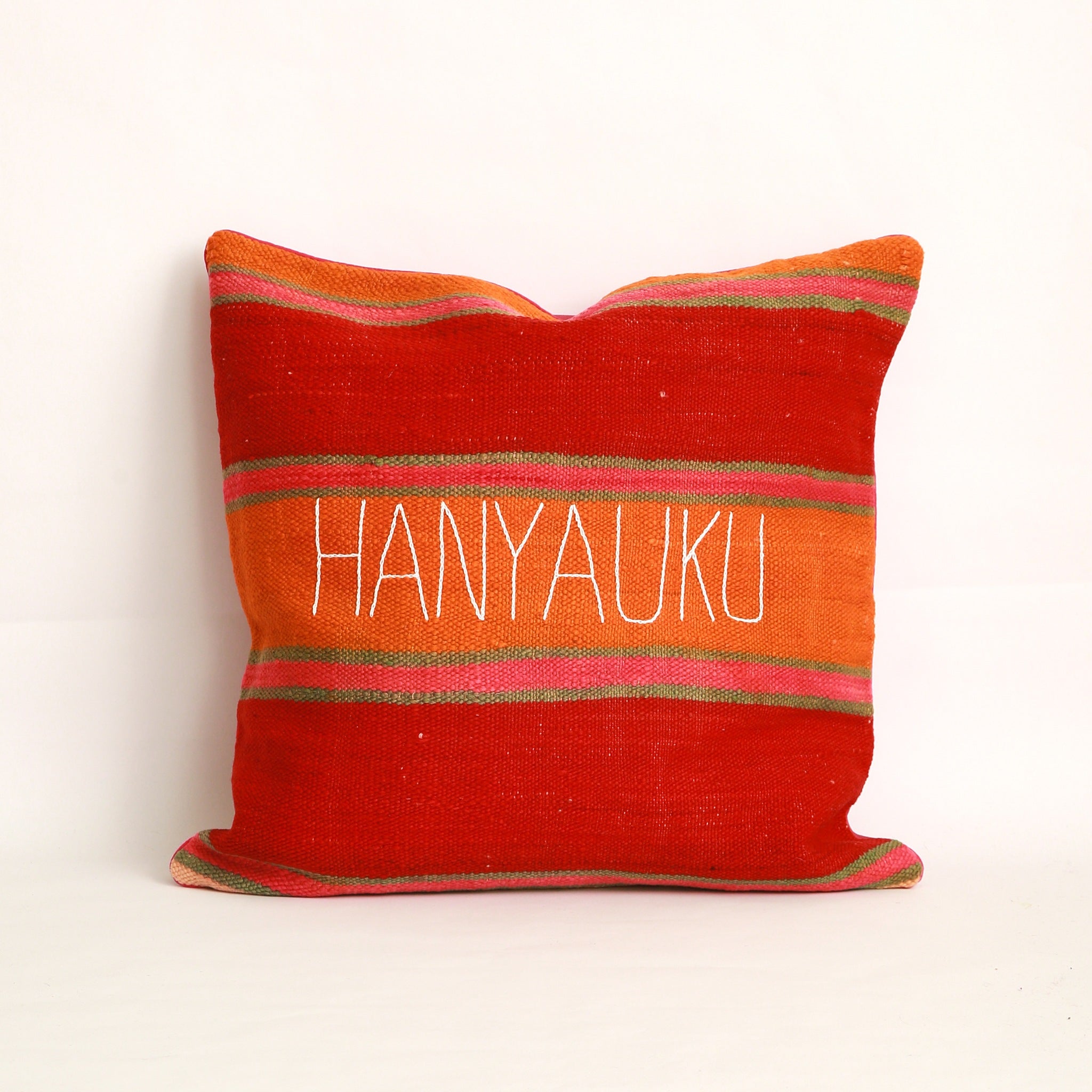 Cuscino realizzato in 2 tessuti, uno diverso da ogni lato: Coperta in lana vintage a righe tessuta a mano nell'Alto Atlante cucita insieme a un cotone rosa scuro tinta unita dall'altro lato - Piping rosa 100% cotone certificato OEKO-TEX®, fronte ricamato a mano con la parola Hanyaku