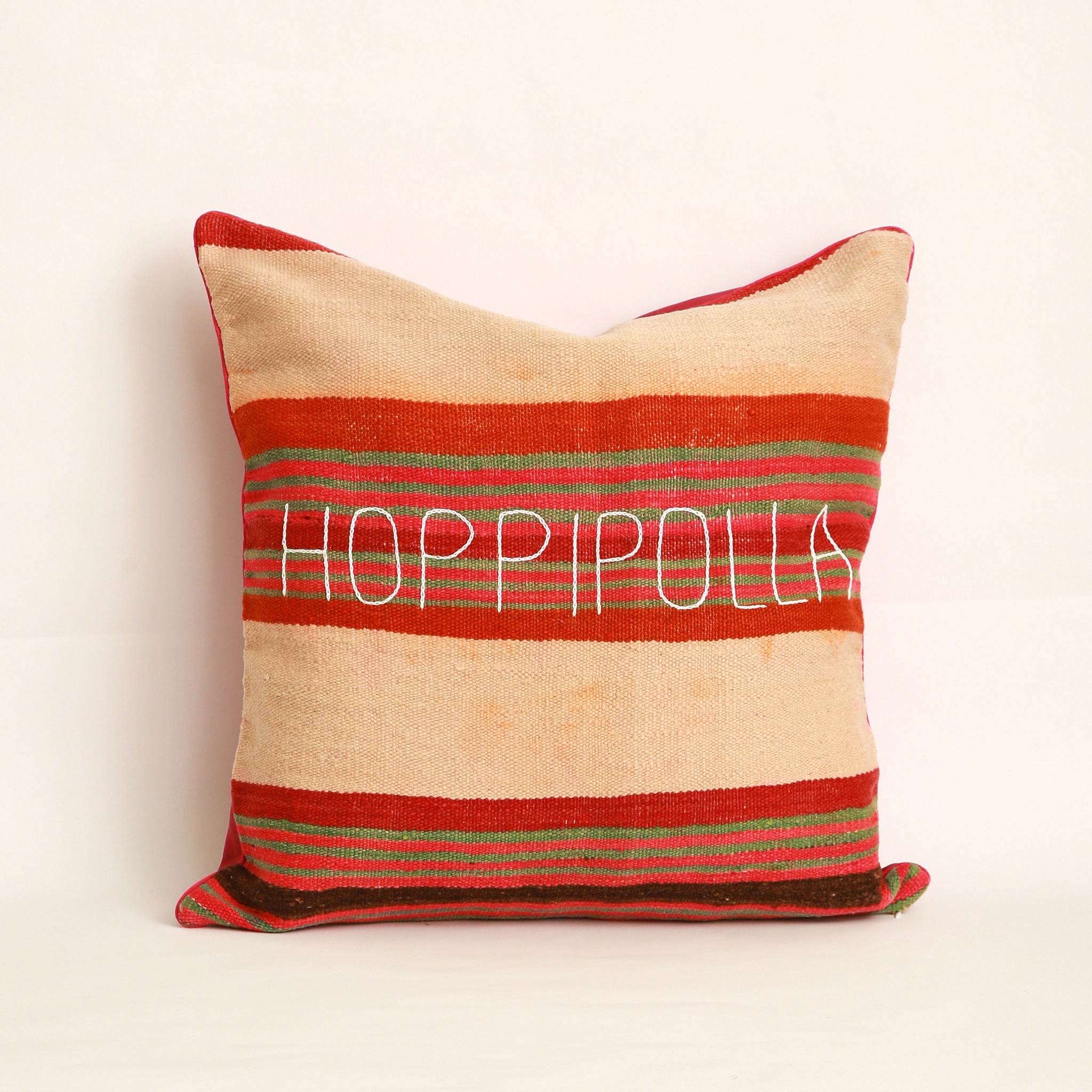 Cuscino realizzato in 2 tessuti, uno diverso da ogni lato: Coperta in lana vintage a righe tessuta a mano nell'Alto Atlante cucita insieme a un cotone rosa scuro tinta unita dall'altro lato - Piping rosa 100% cotone certificato OEKO-TEX®, fronte ricamato a mano con la parola Hoppipolla