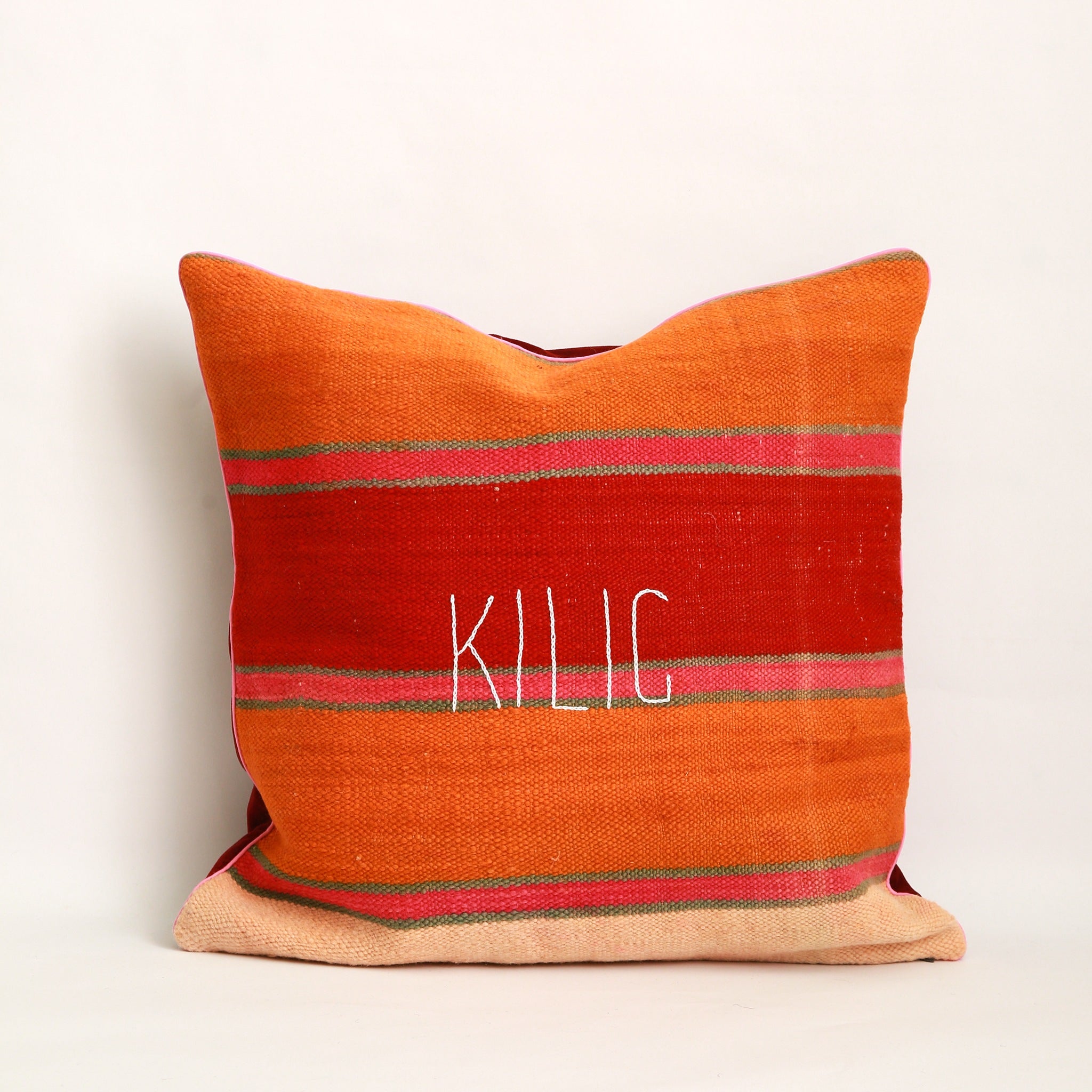 Copricuscino realizzato con 2 tessuti, uno diverso da ogni lato. Sul lato mostrato, coperta vintage tessuta a mano in Marocco, a righe colorate arancione rosso rosa e verde acqua, ricamo a mano con la parola Kilig, bordo tutto attorno al cuscino piping in cotone rosa chiaro