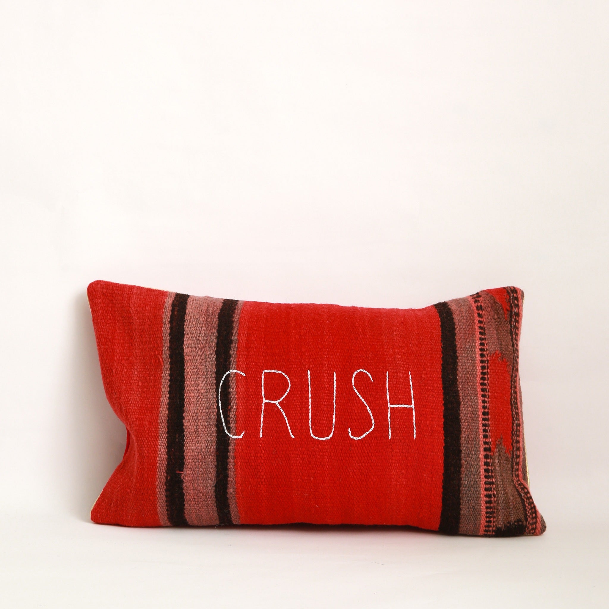 Copricuscino decorativo particolare cucito con due tessuti diversi, uno da ogni lato, un lato con coperta in morbida lana a righe colorate nere, rosse e marrone chiaro e altro lato in velluto rosso, per cuscino 30x50cm, il lato in lana è ricamato a mano, con la parola Crush, chiusura con cerniera.