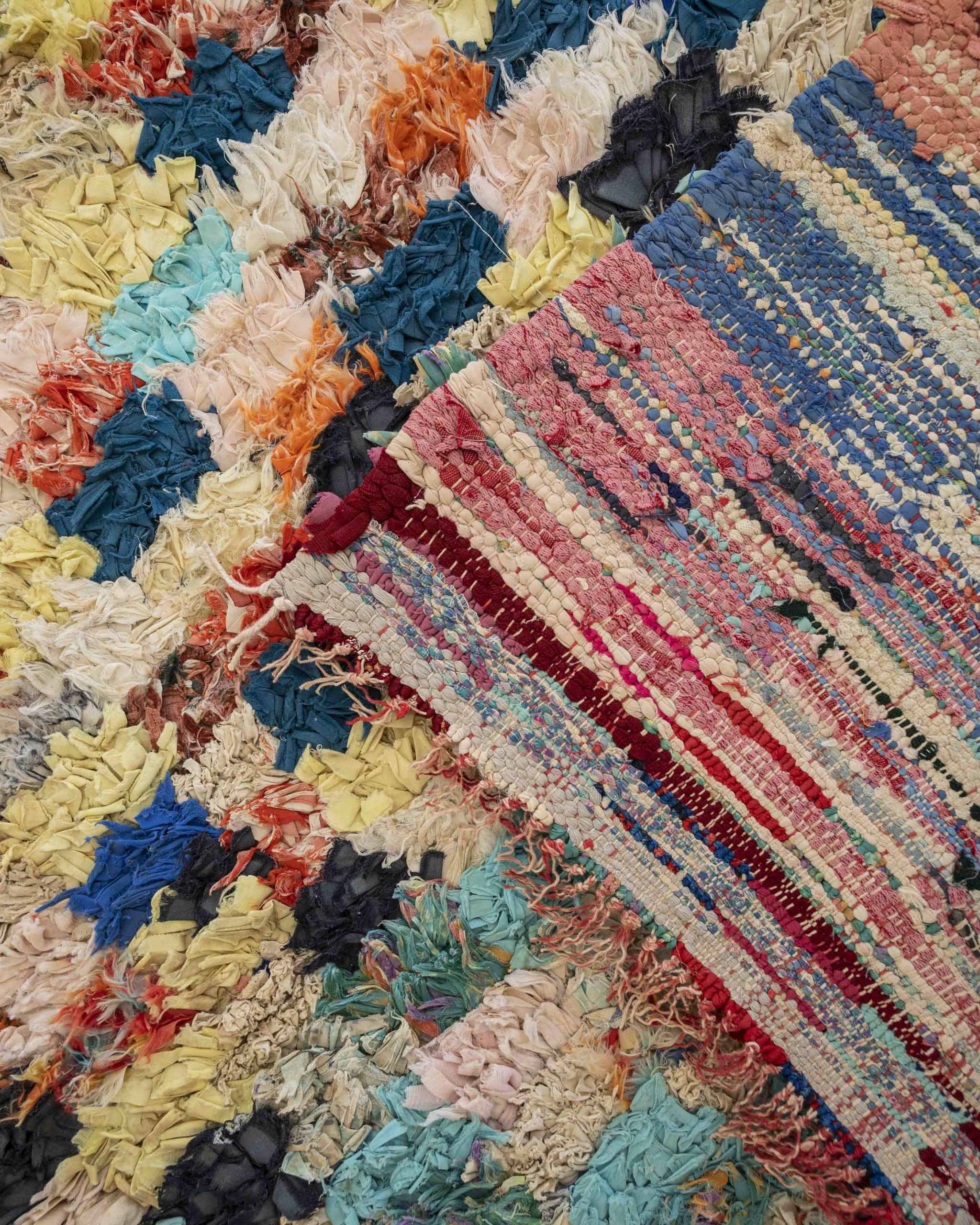 Dettaglio retro tappeto con fettucce di tessuto multicolore annodate e orlo a frange