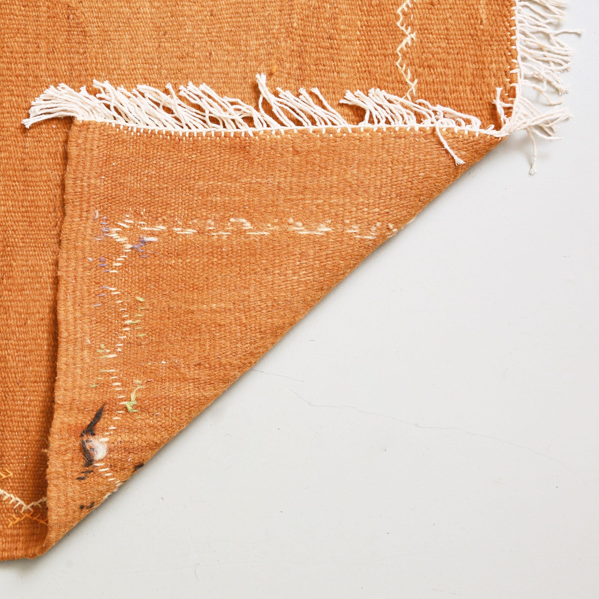 Back view of Akhnif kilim rug showing natural white cotton fringes and flat-weave construction of handwoven Moroccan carpet with visible geometric pattern from reverse side