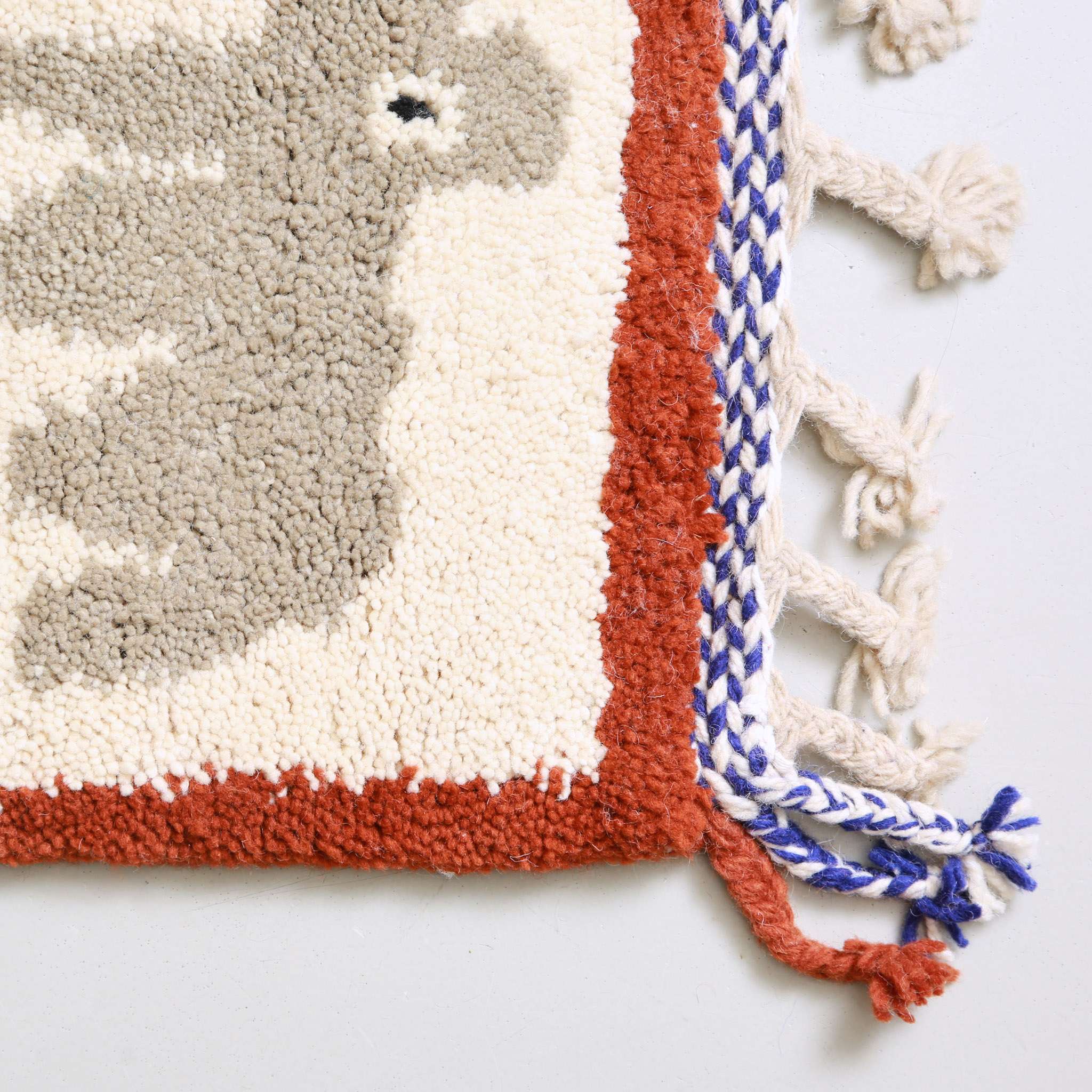 Dettaglio angolo tappeto berbero con bordatura terracotta e frange multicolori, artigianato autentico marocchino