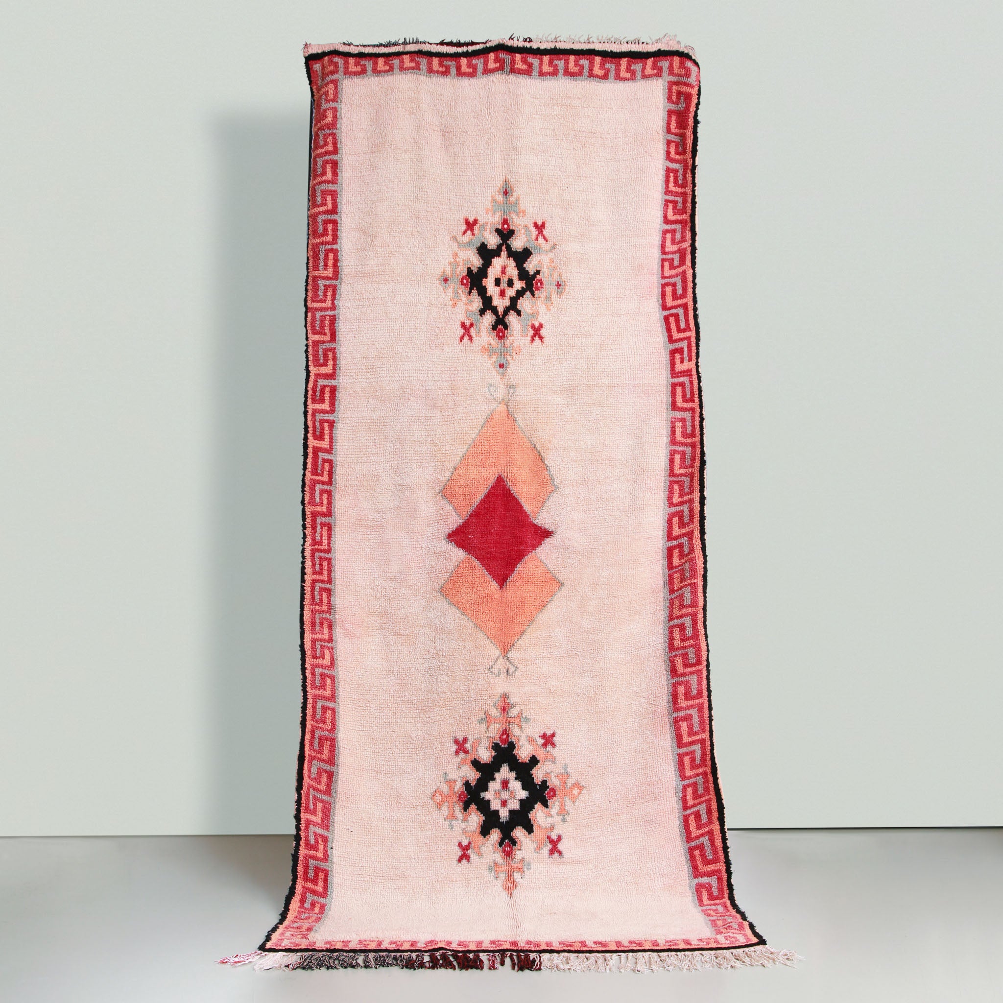 tappeto azilal vintage su base chiara con cornice arancione e rossa e un disegno geometrico centrale con un quadrao rosso che copre una parte di due quadrati arancioni e sopra e sotto in disegno astratto