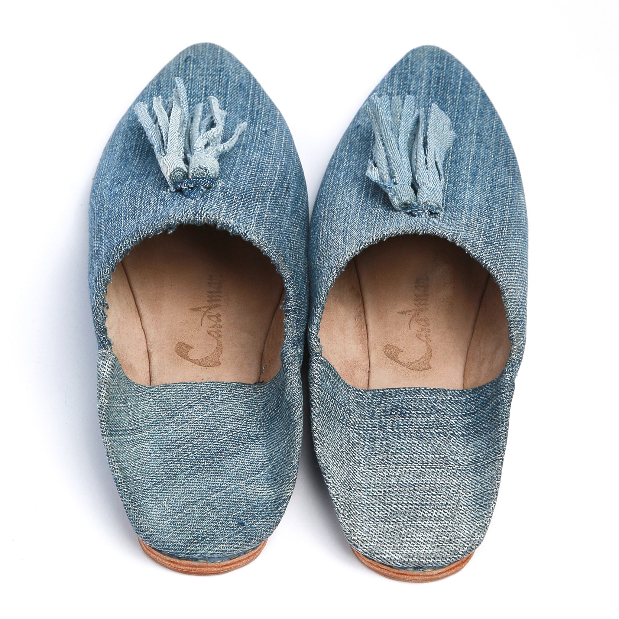 coppia di babouche realizzate a mano in marocco in jeans chiaro con pompon in jeans viste dall'alto