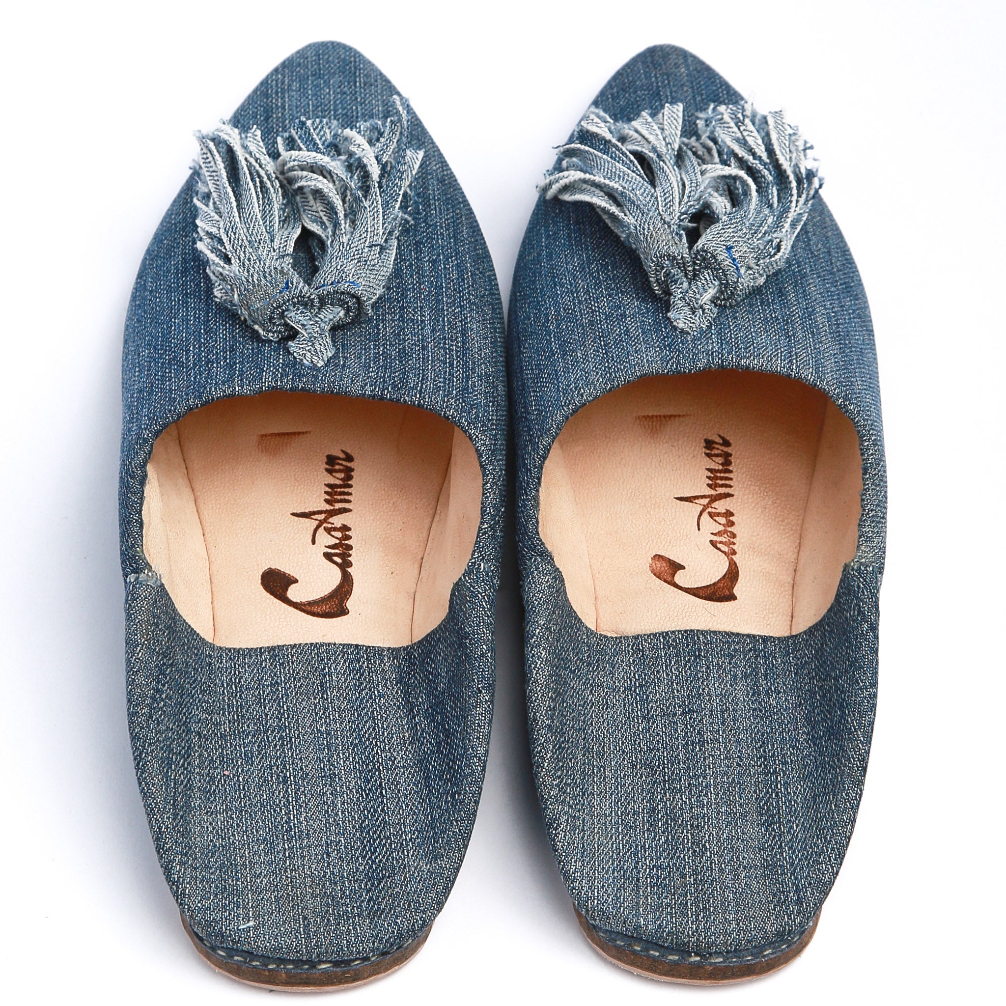 coppia di babouches marocchine in denim scuro con pompon viste dall'alto