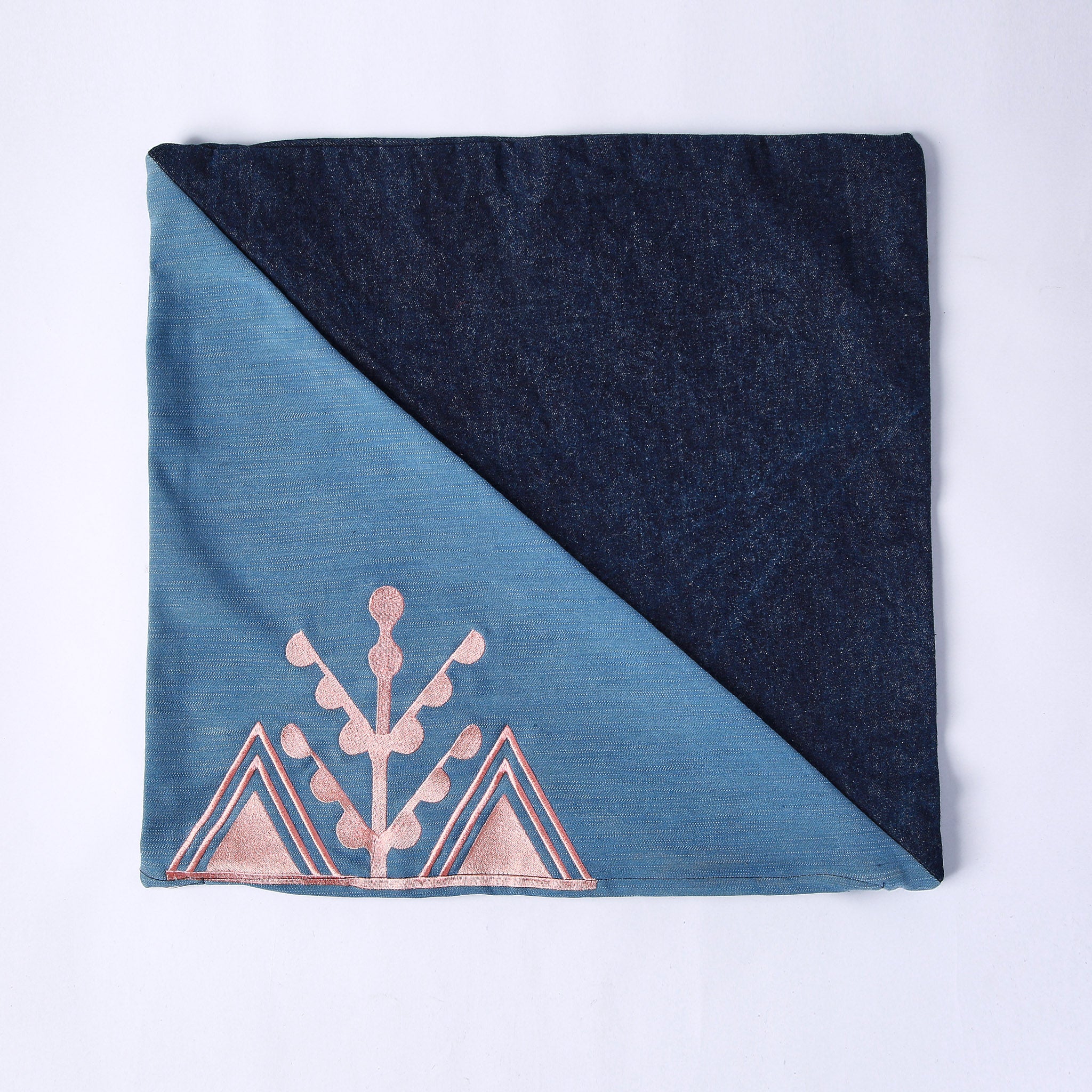 cuscino quadrato realizzato con tessuti in jeans di due colori e ricamo rosa del simbolo amazigh dell'ulivo