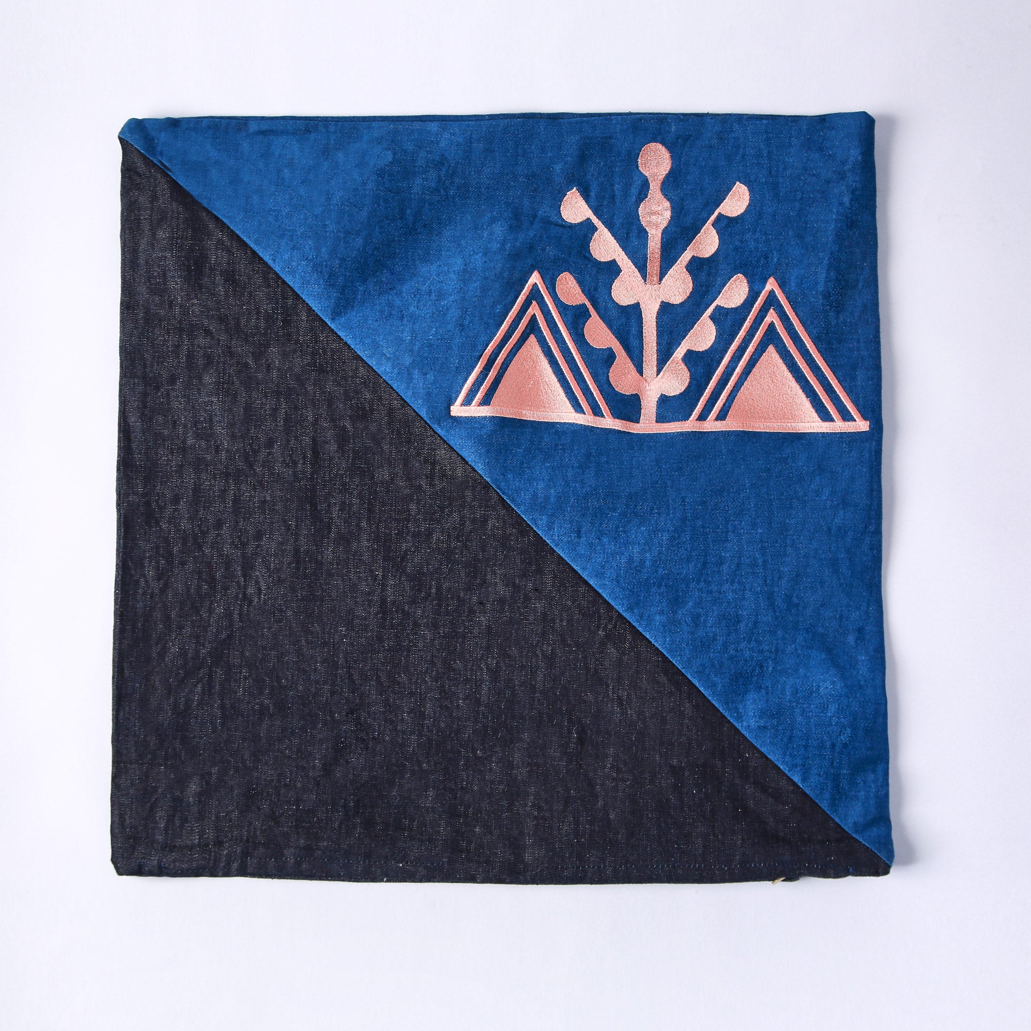 cuscino quadrato realizzato con tessuti in jeans di due colori e ricamo rosa del simbolo amazigh dell'ulivo