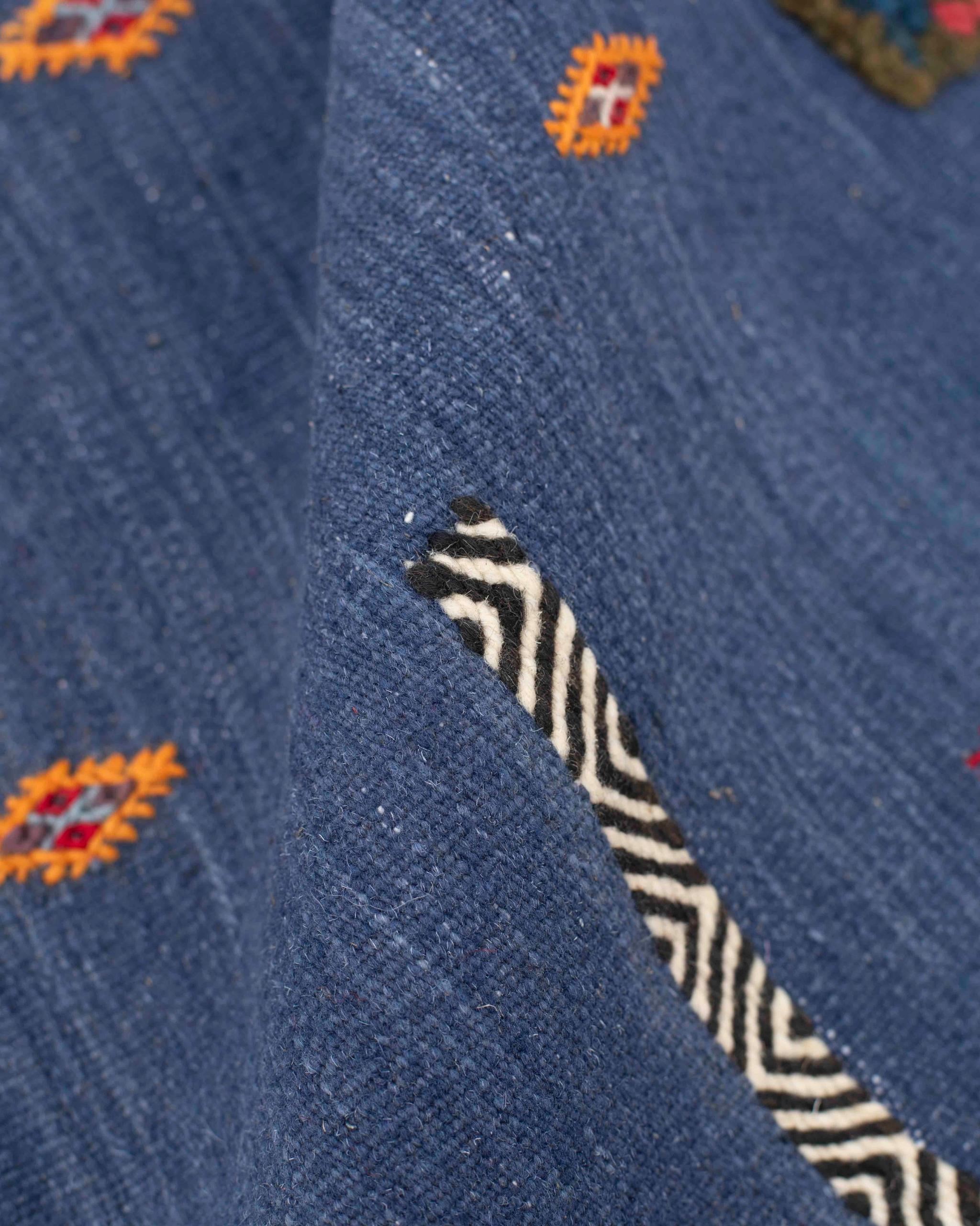 Dettaglio della fascia bianca e nera a chevron sul tappeto kilim blu marocchino