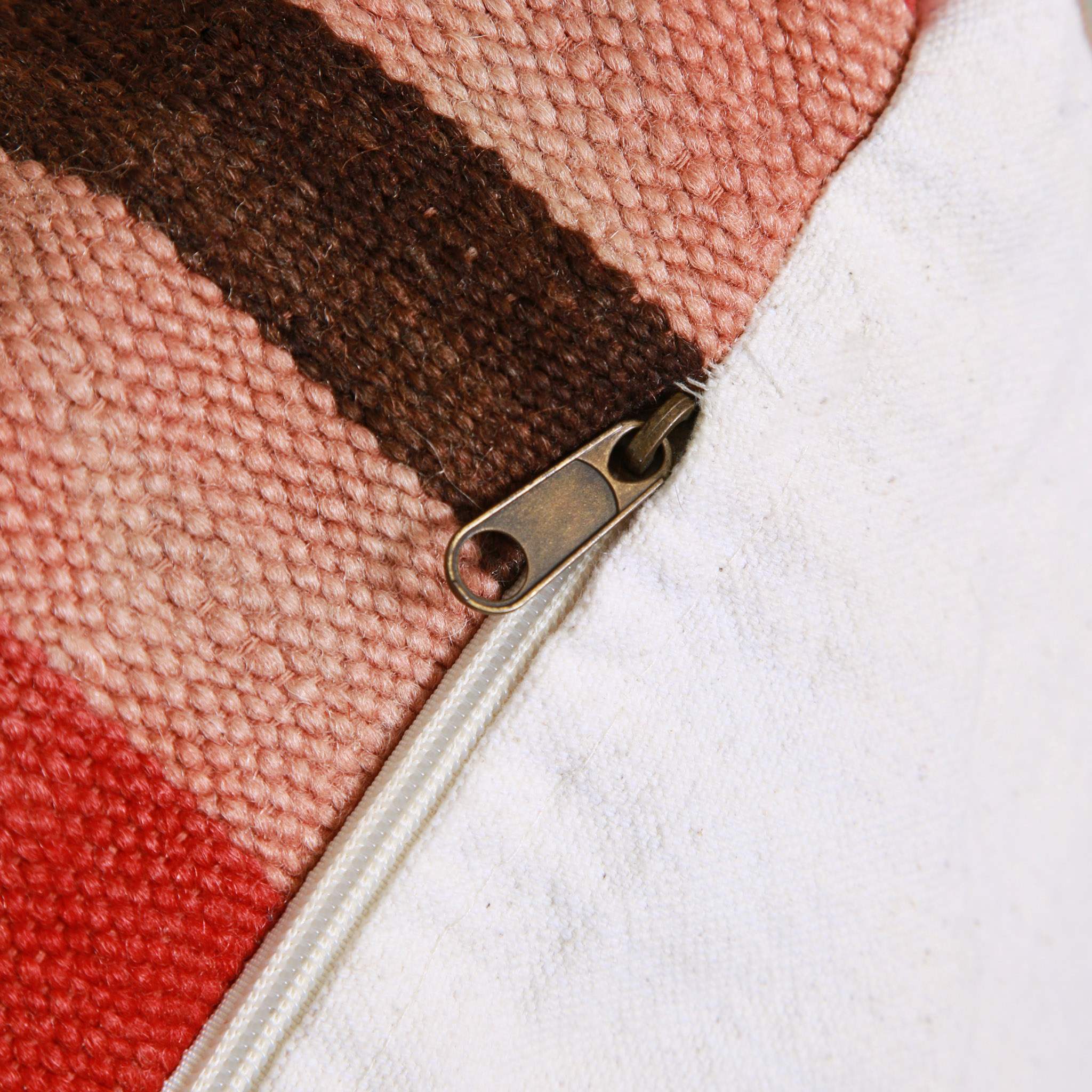 Dettaglio della chiusura a zip in metallo del pouf marocchino in tessuti kilim riciclati con trame in corallo e marrone, cuciture artigianali