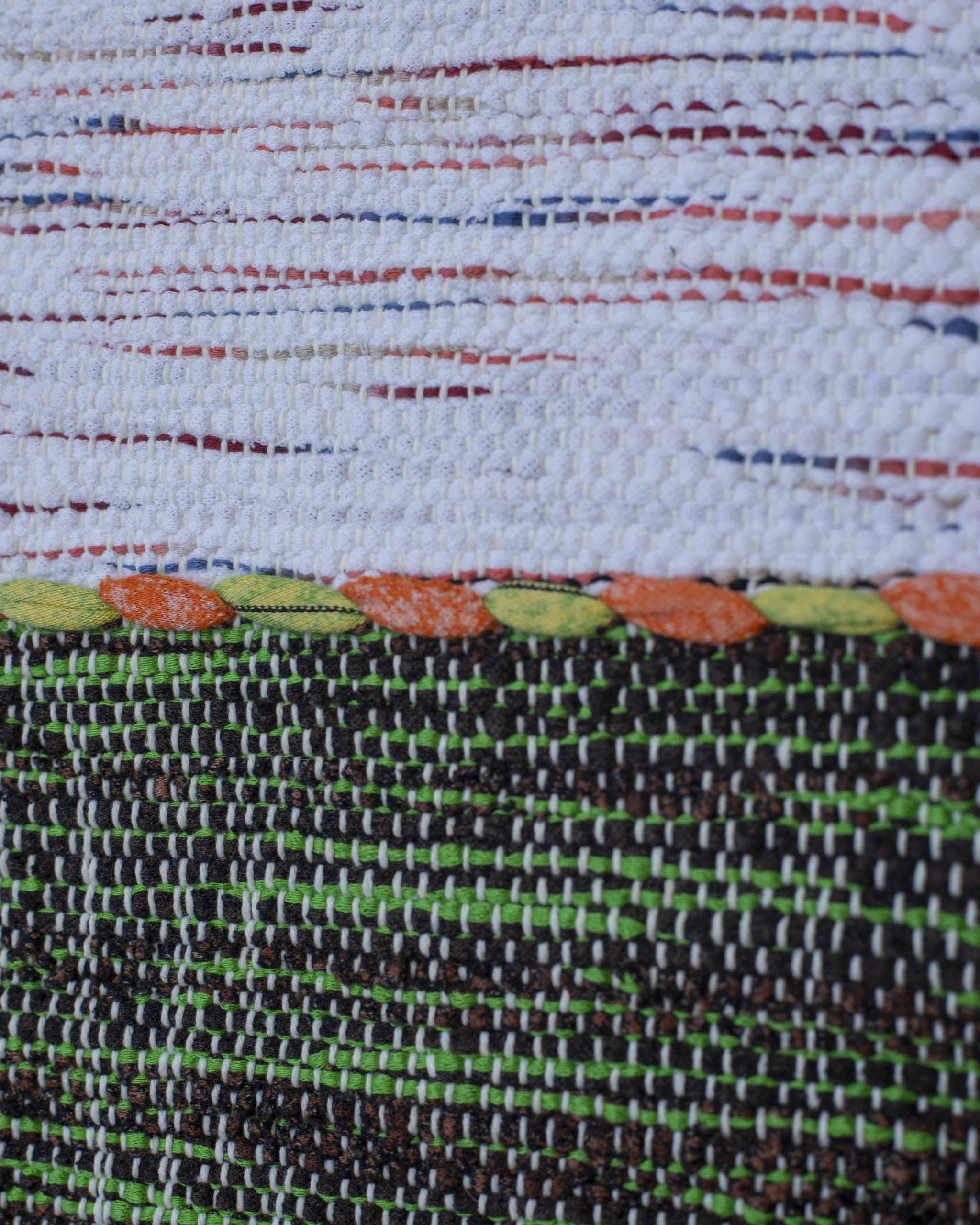 Dettaglio del tessuto melange di cui è fatto il cuscino decorativo bianco e verde con microvariazioni multicolore