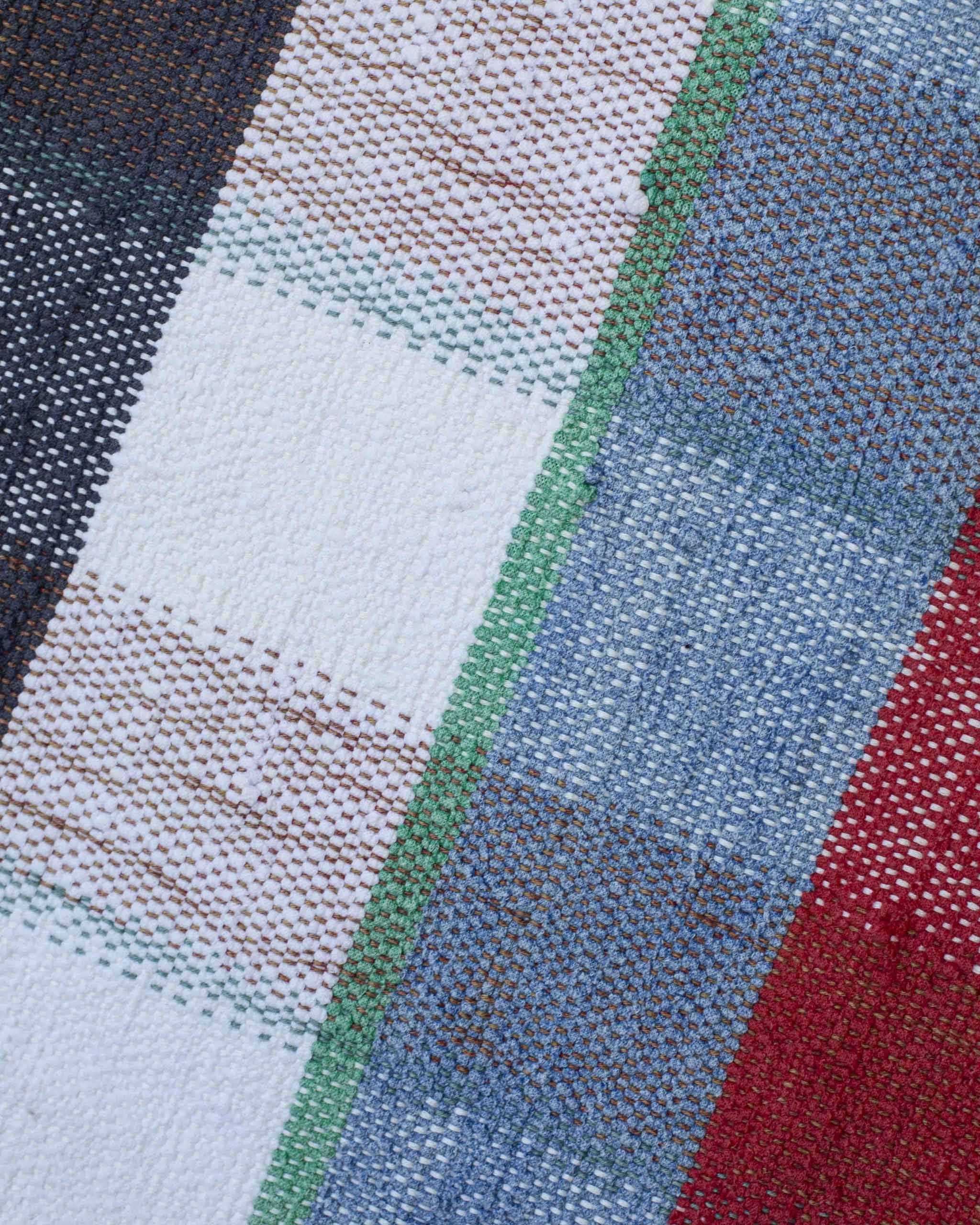 Dettaglio dei filati melange che compongono la fodera del cuscino a quadri bianchi, azzurri, blu, rossi