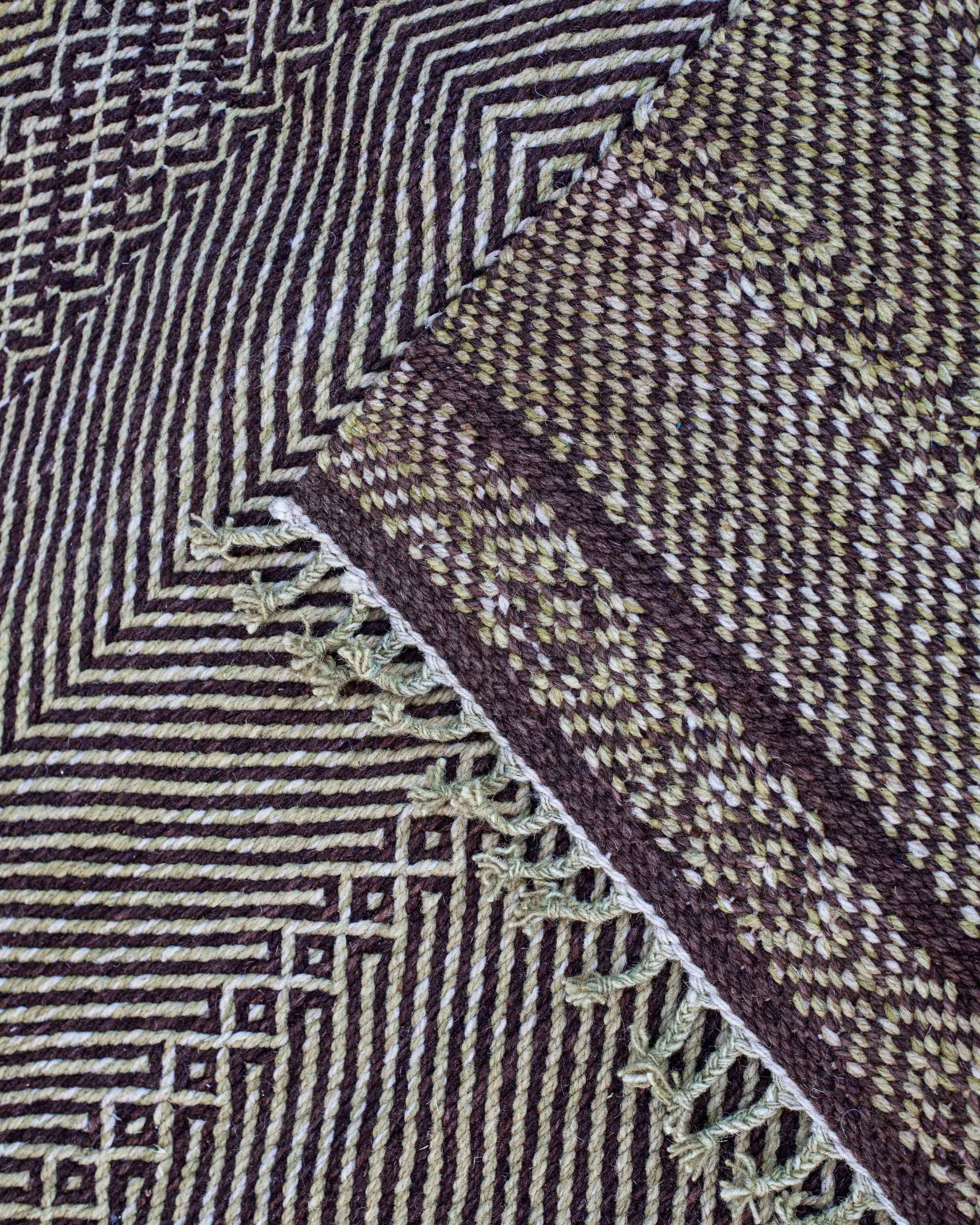 Dettaglio fronte-retro e frange del tappeto Zanafi in lana, trama fitta bicolore con disegni geometrici