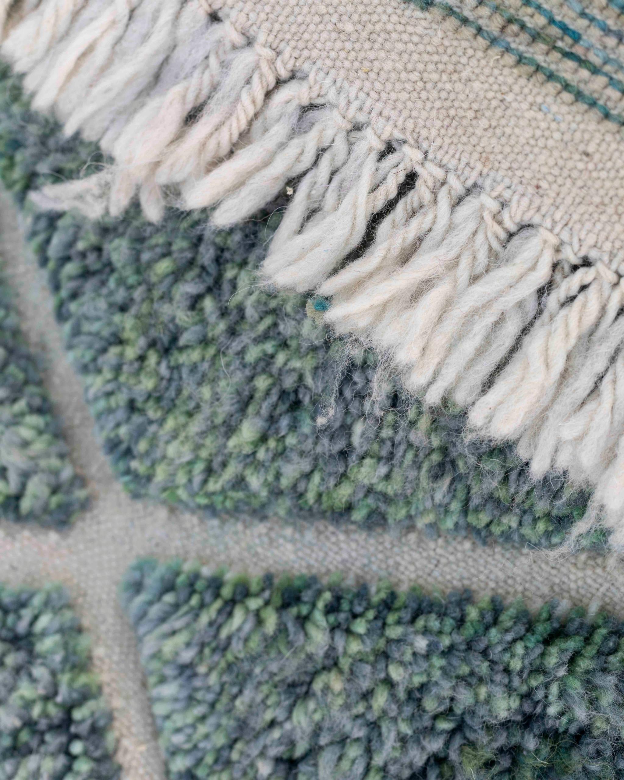 Dettaglio delle frange chiare e del bordo di un tappeto Beni Ourain verde blu petrolio