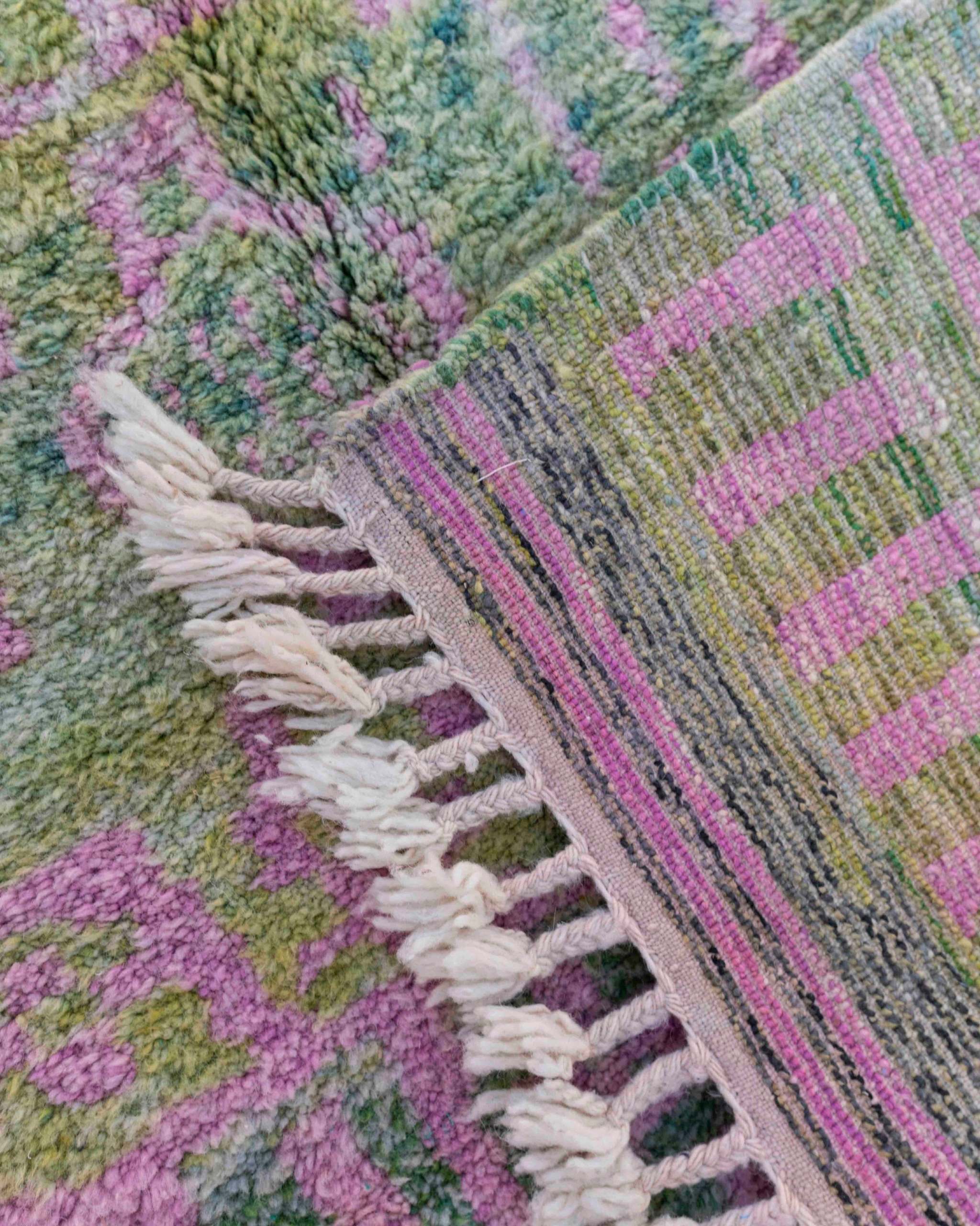 Dettaglio delle maxi frange intrecciate e del rovescio del tappeto Beni Ourain in lana verde e rosa
