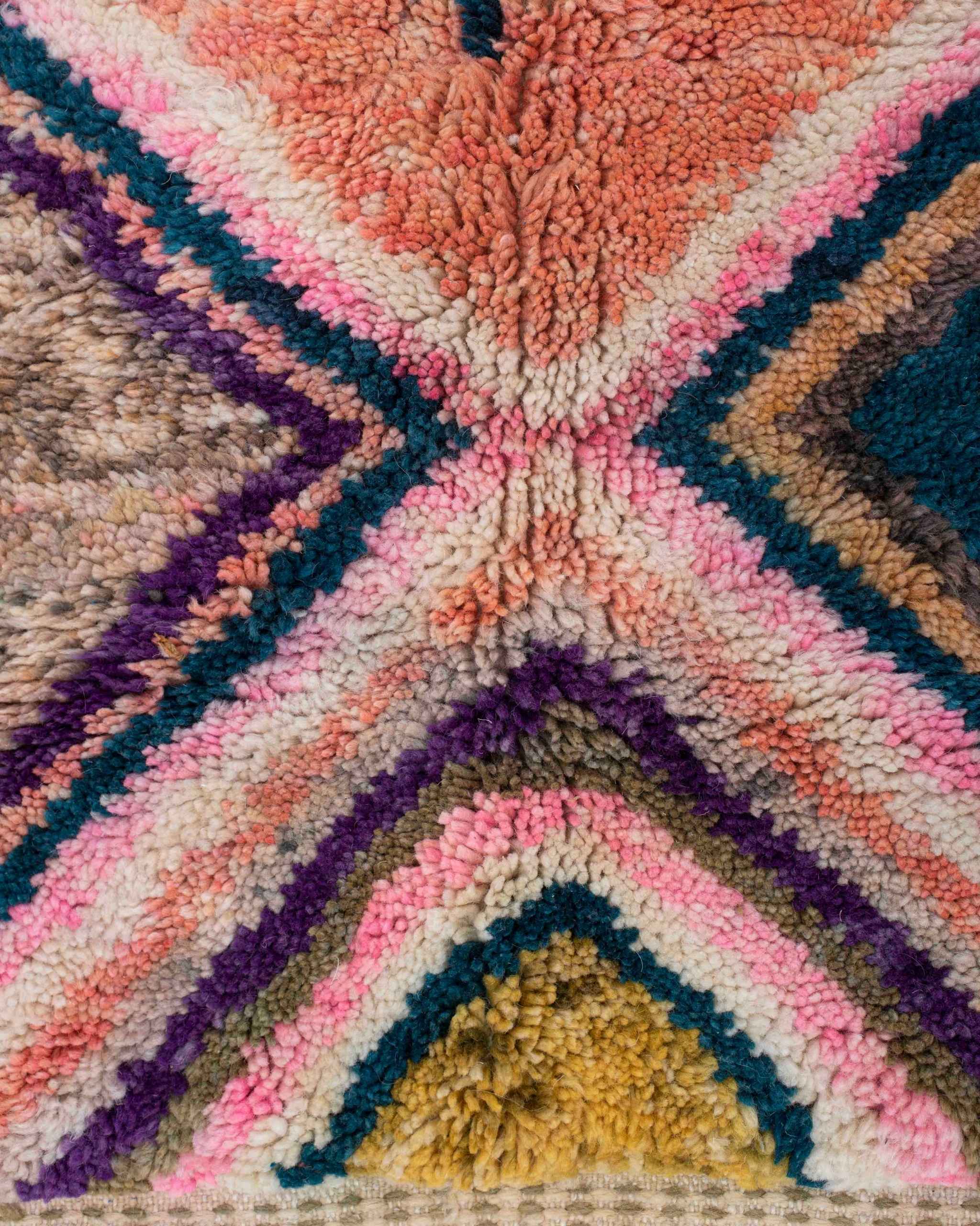 Dettaglio della geometria a rombi del tappeto Beni Ourain in lana rosa, corallo, ocra, blu e viola