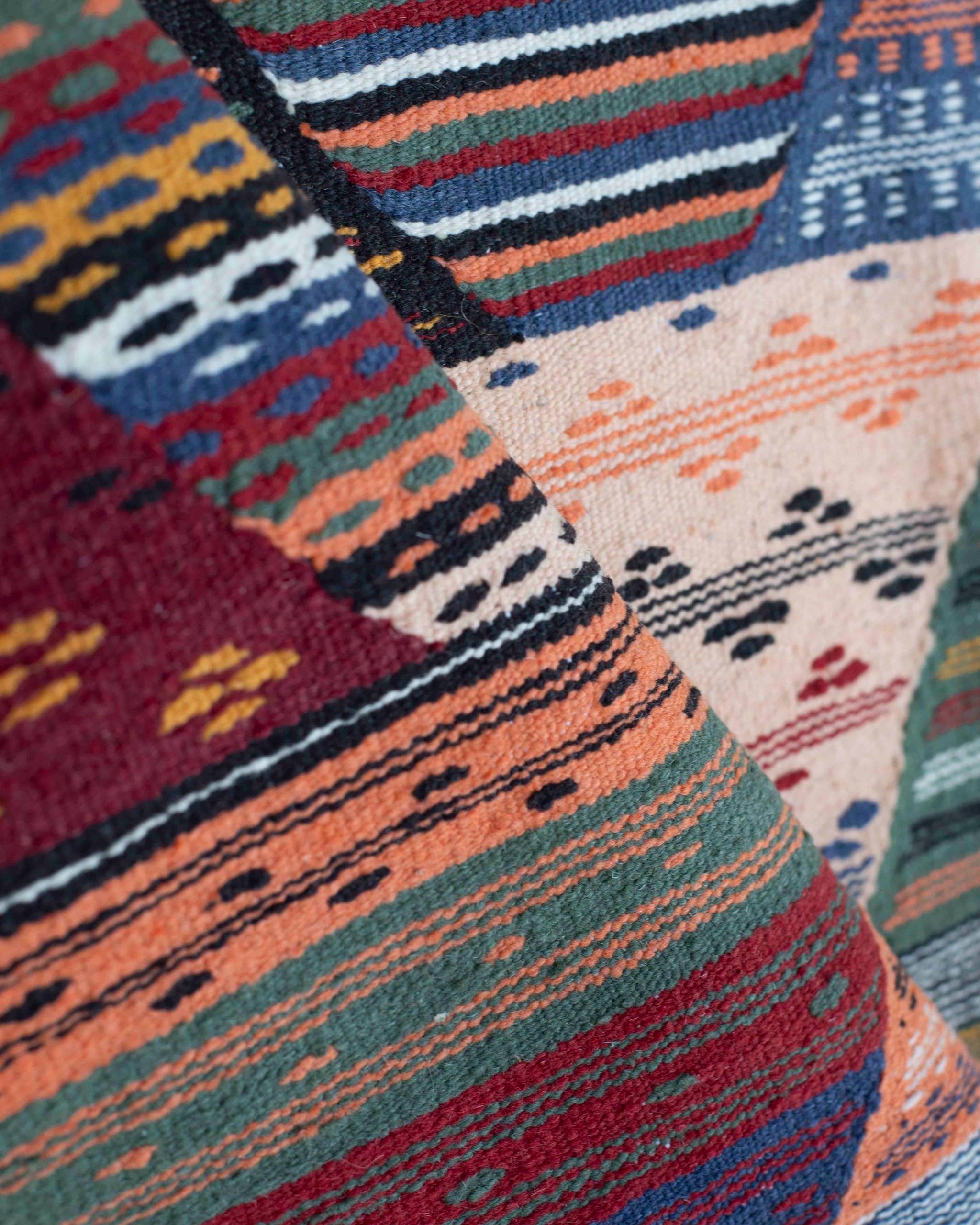 Dettaglio del kilim marocchino in lana multicolore con pattern geometrico a triangoli, rombi, linee, punti