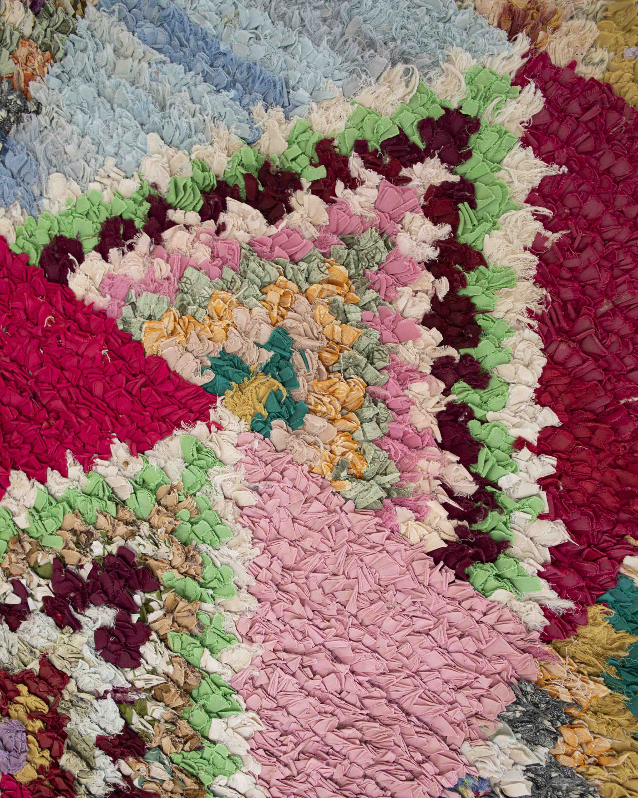 Dettaglio del tappeto runner fatto a mano con strisce di stoffe miste in colori pastello e fantasia a quadretti e triangoli