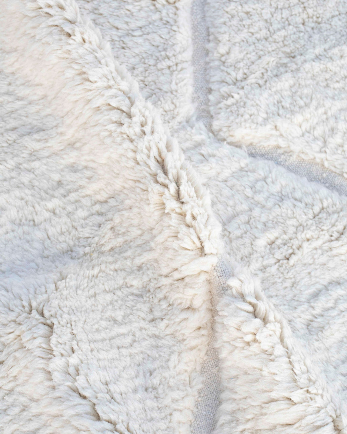 Dettaglio tappeto bianco in lana a pelo medio-lungo con linee a tessitura piatta