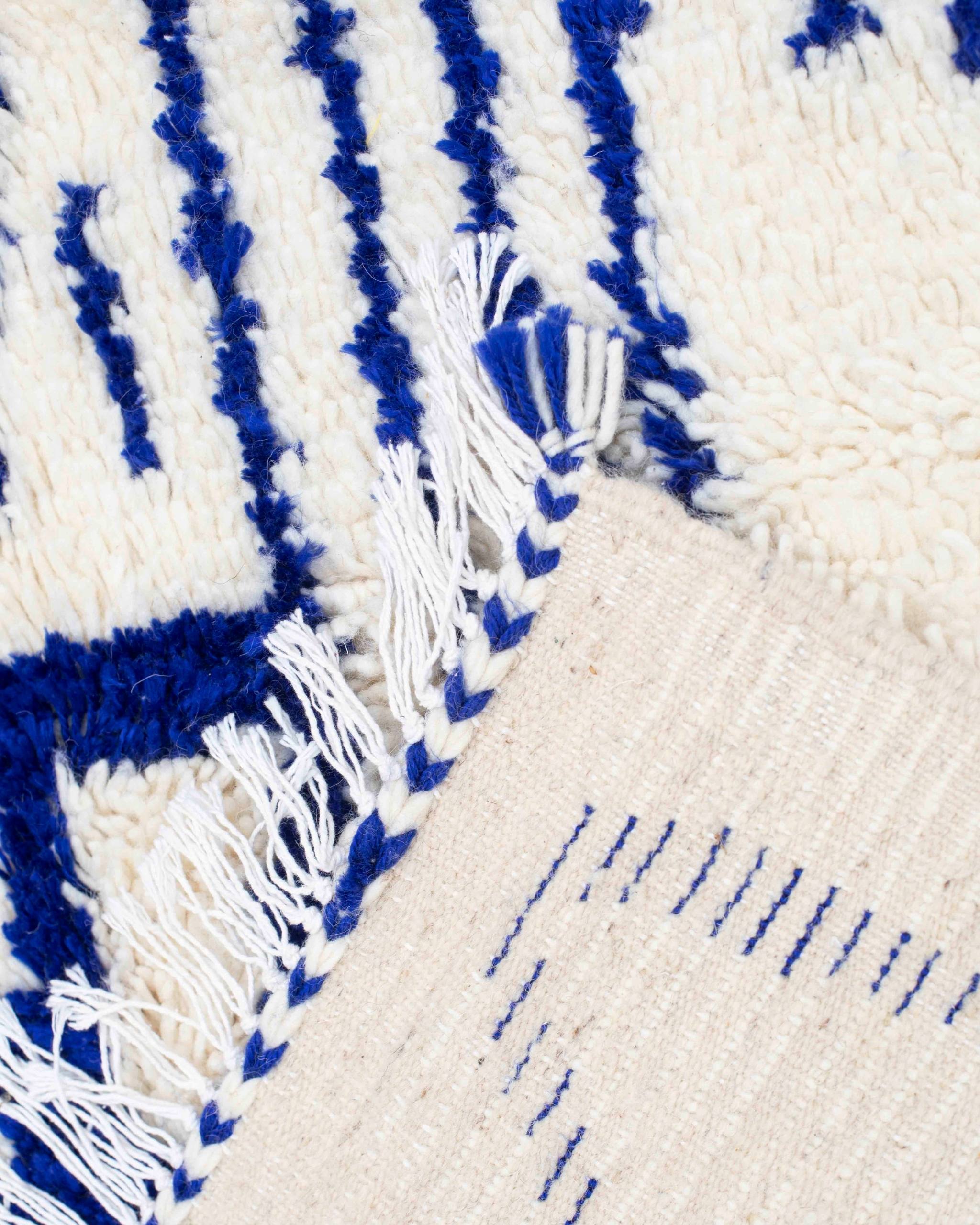 Dettaglio del retro e delle frange del tappeto Azilal bianco con motivi blu Majorelle