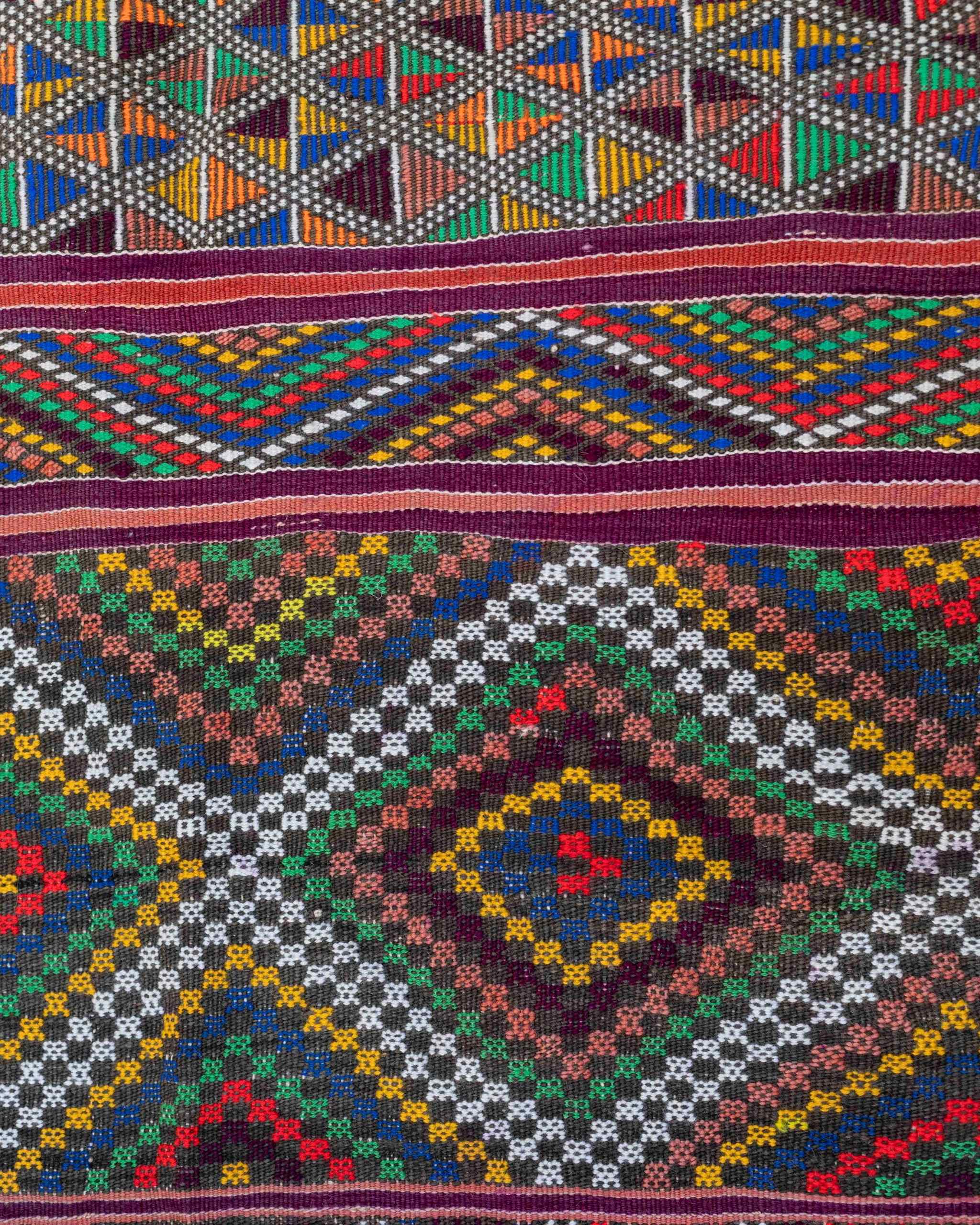 Dettaglio dei rombi multicolore e dei triangoli del tappeto berbero in lana blu, rosso, verde, giallo, rosa, viola e bianco