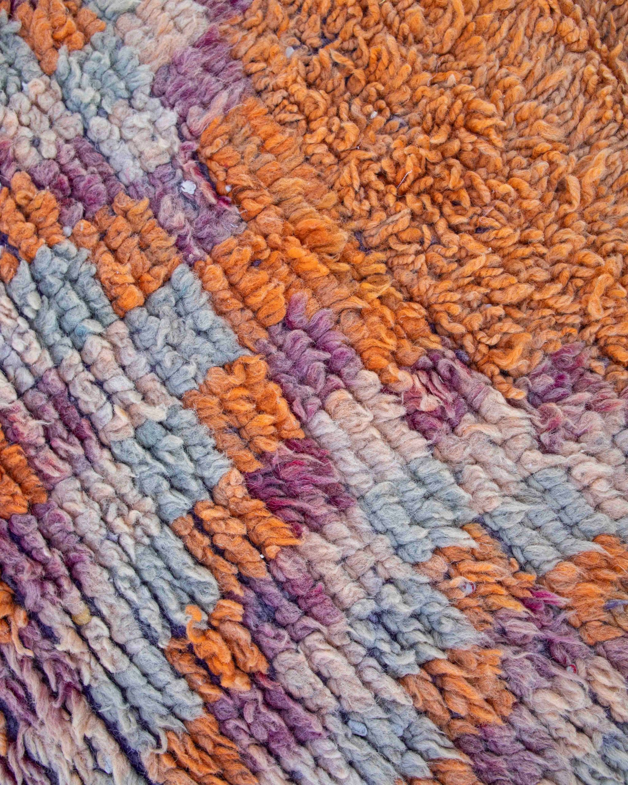 Dettaglio del rombo arancione e della cornice a quadretti in colori pastello del piccolo tappeto Boujaad vintage in lana