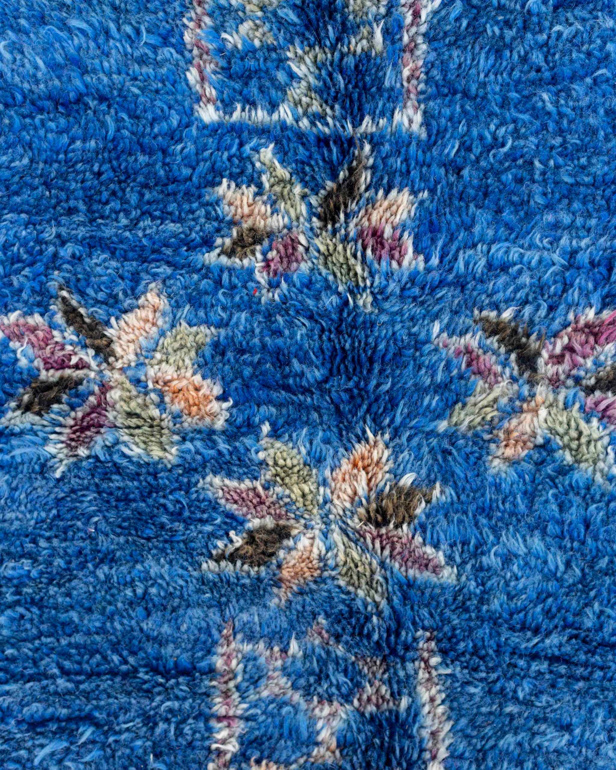 Dettaglio del tappeto blu vintage con pattern geometrico e simboli berberi policromi