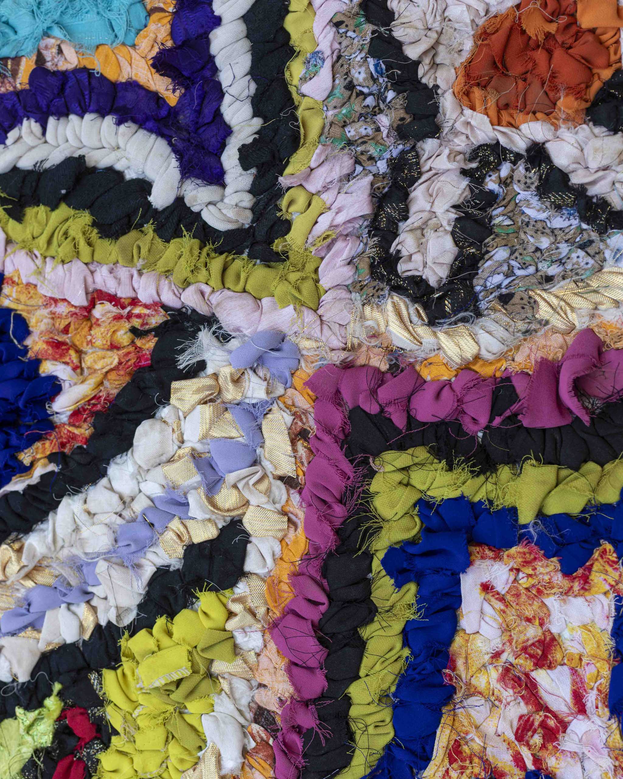 Dettaglio della superficie del tappetino in tessuti annodati di tantissimi colori e materiali