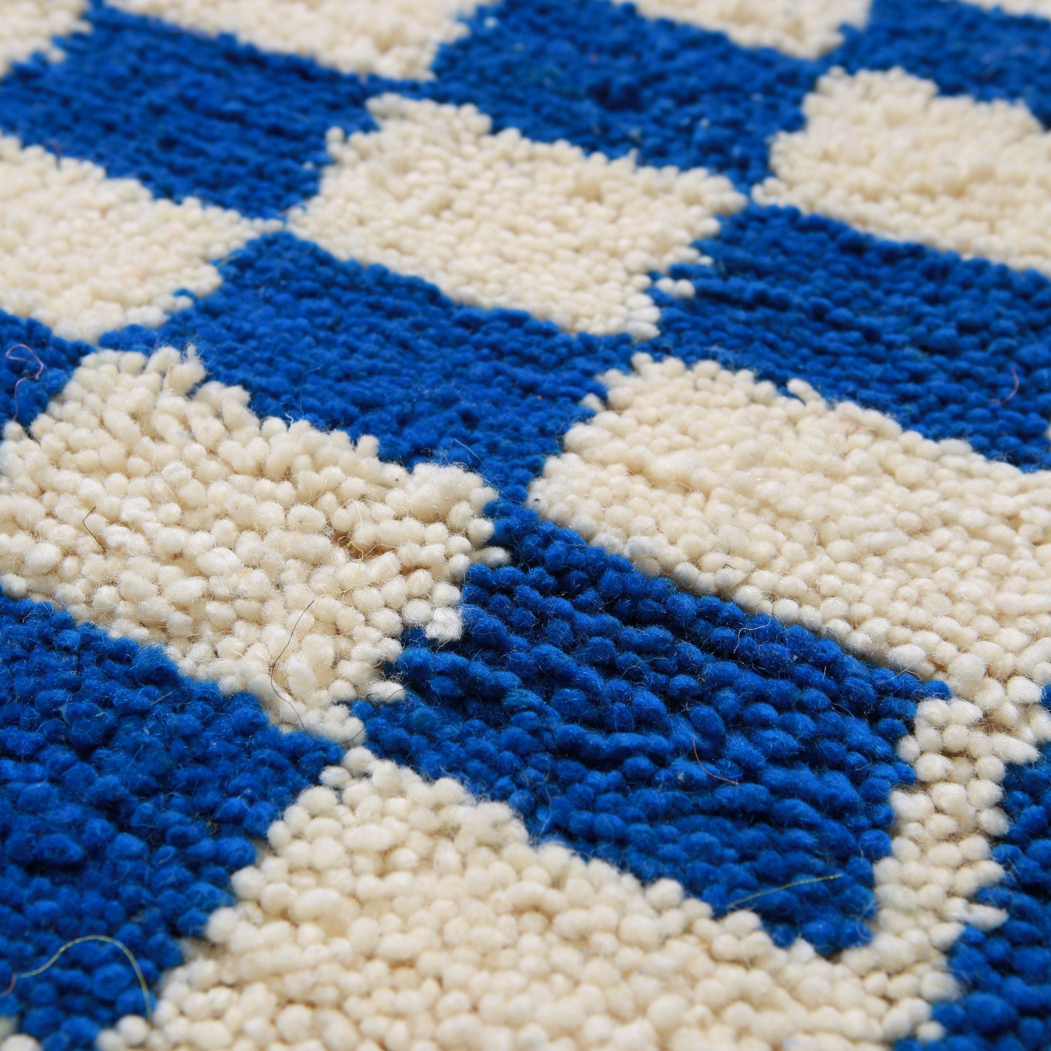 Dettaglio del pelo medio-corto del tappeto Azilal con pattern geometrico a scacchi blu e crema