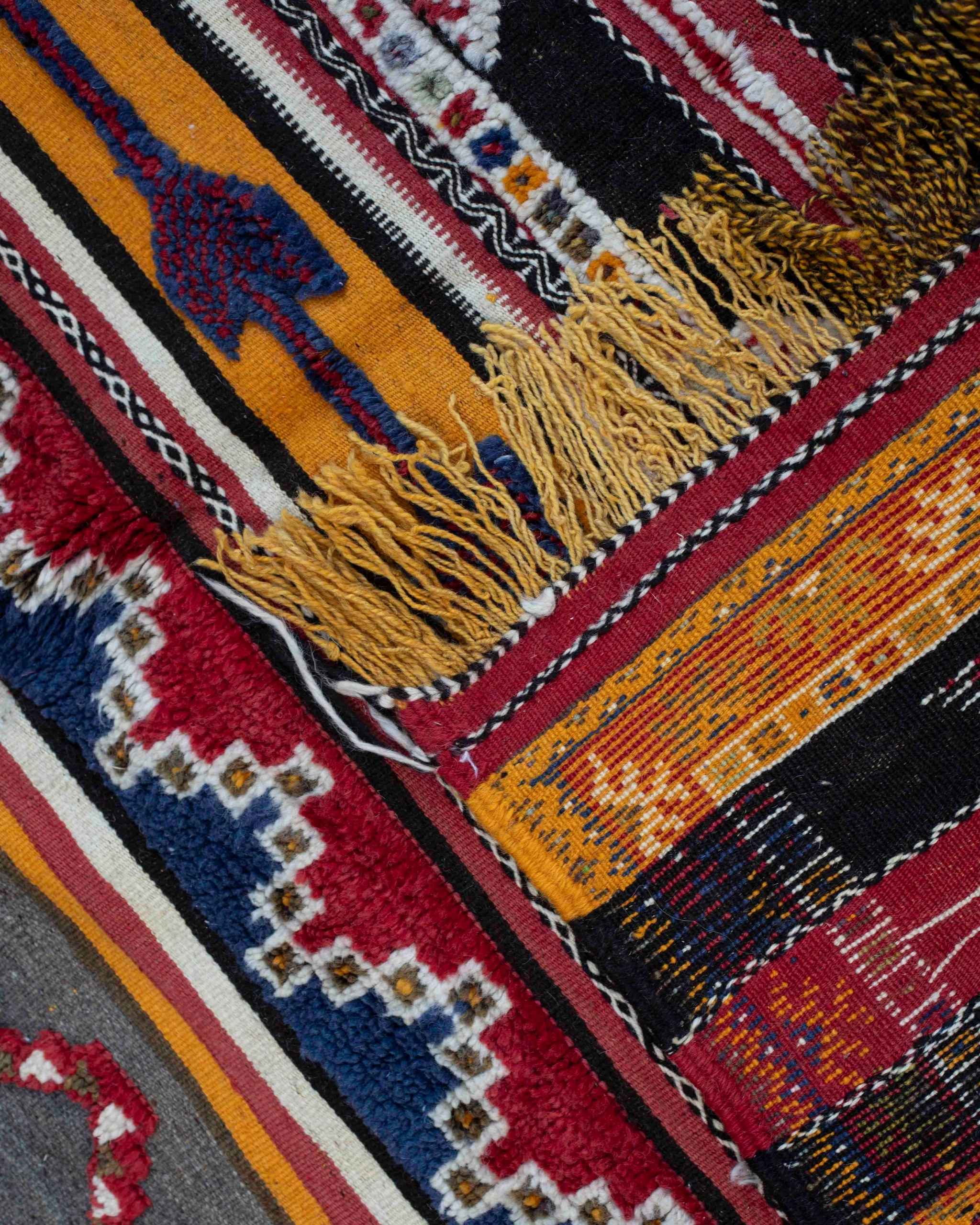 Dettaglio del tappeto etnico Glaoui in colori primari e secondari, con frange giallo-nere