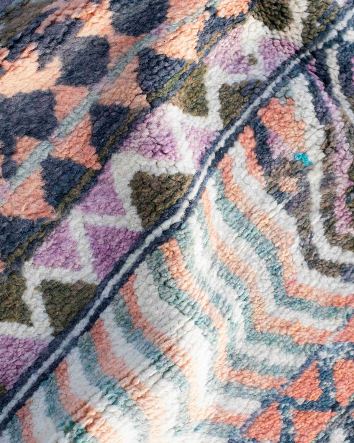Dettaglio del tappeto in lana annodata a pelo corto con fantasia geometrica colorata a zigzag, triangoli, righe, linee ondulate