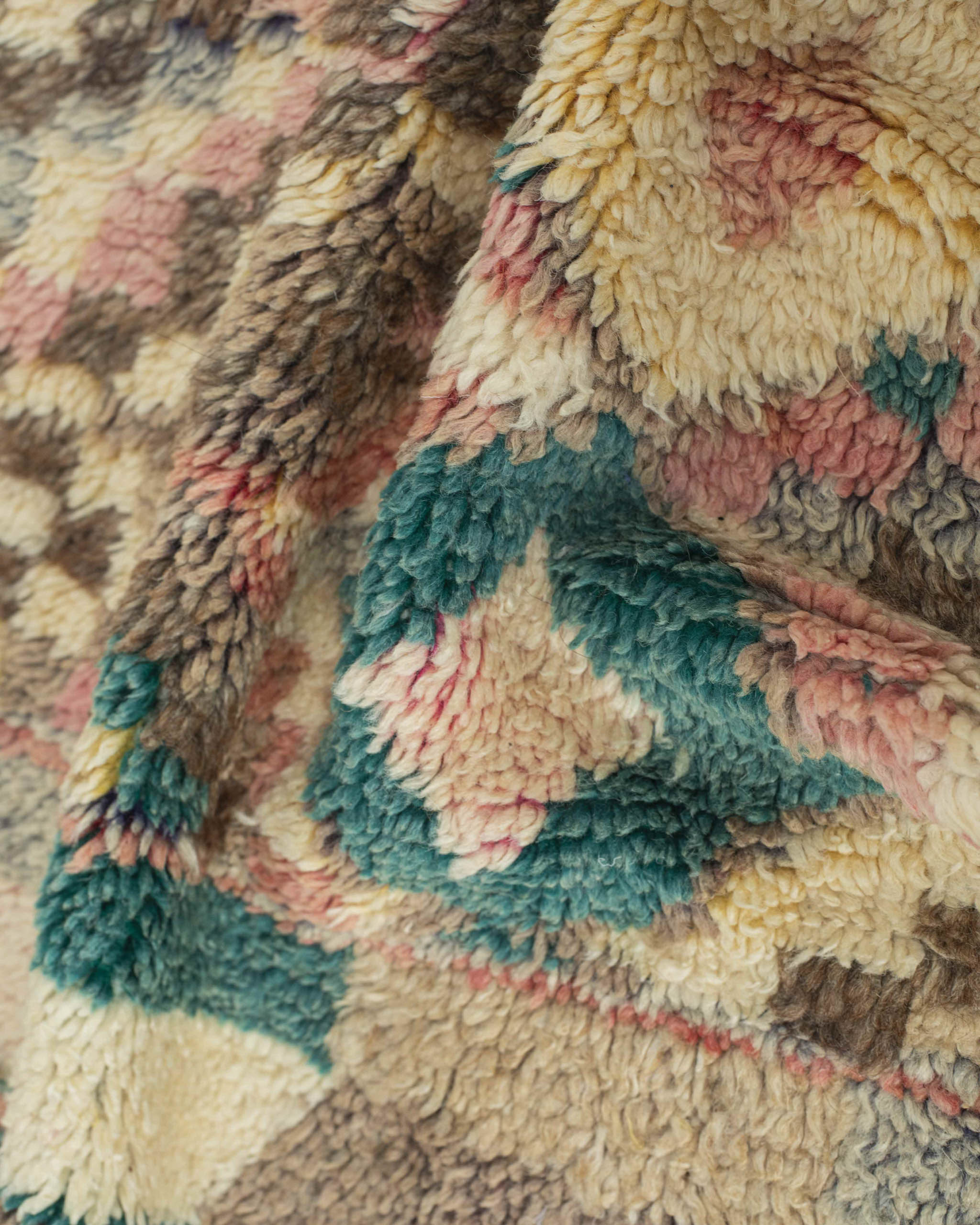 Dettaglio del tappeto in lana a vello corto con rombi beige verde petrolio rosa marrone