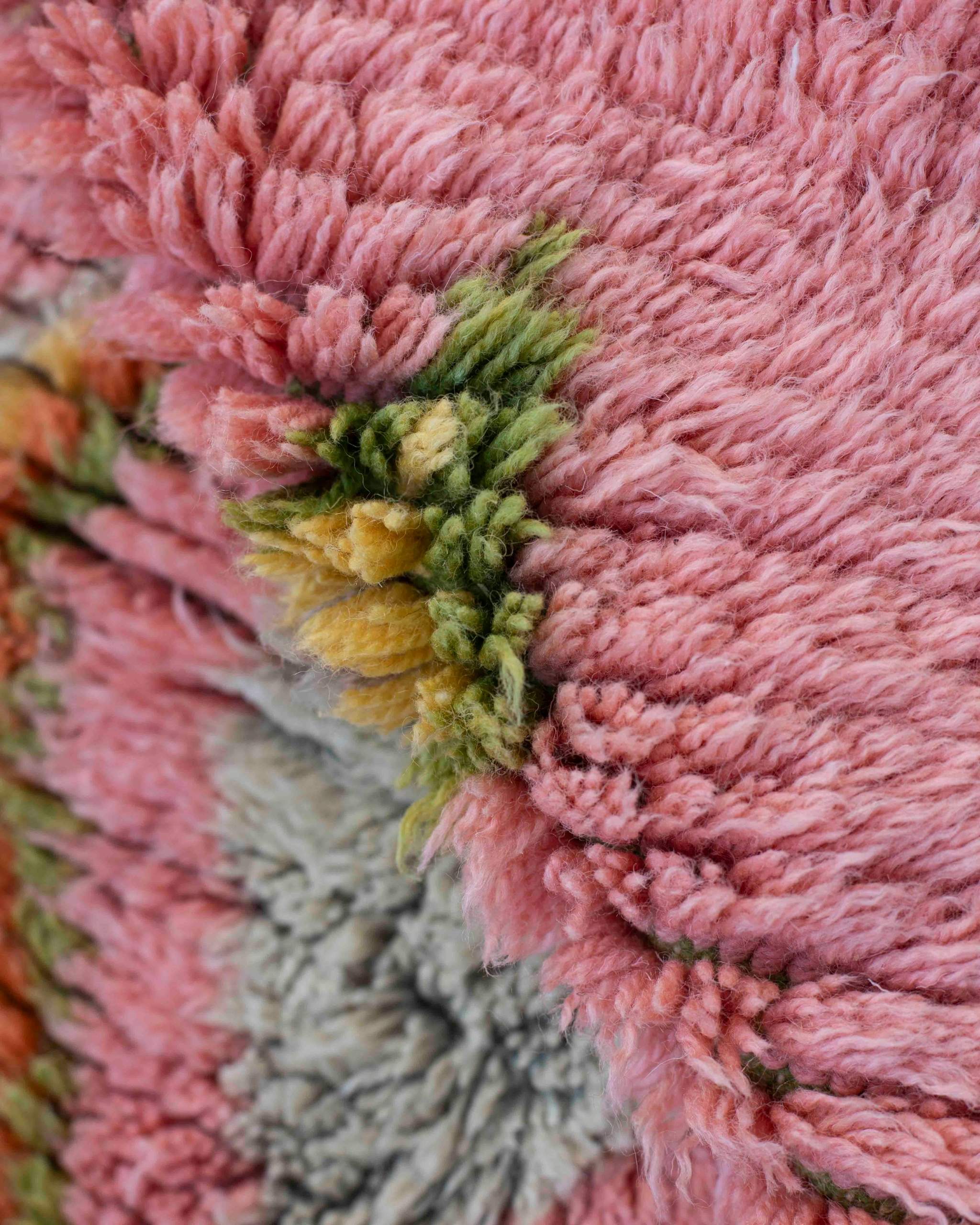 Dettaglio del tappeto in pura lana a pelo corto rosa, verde, gialla, grigia