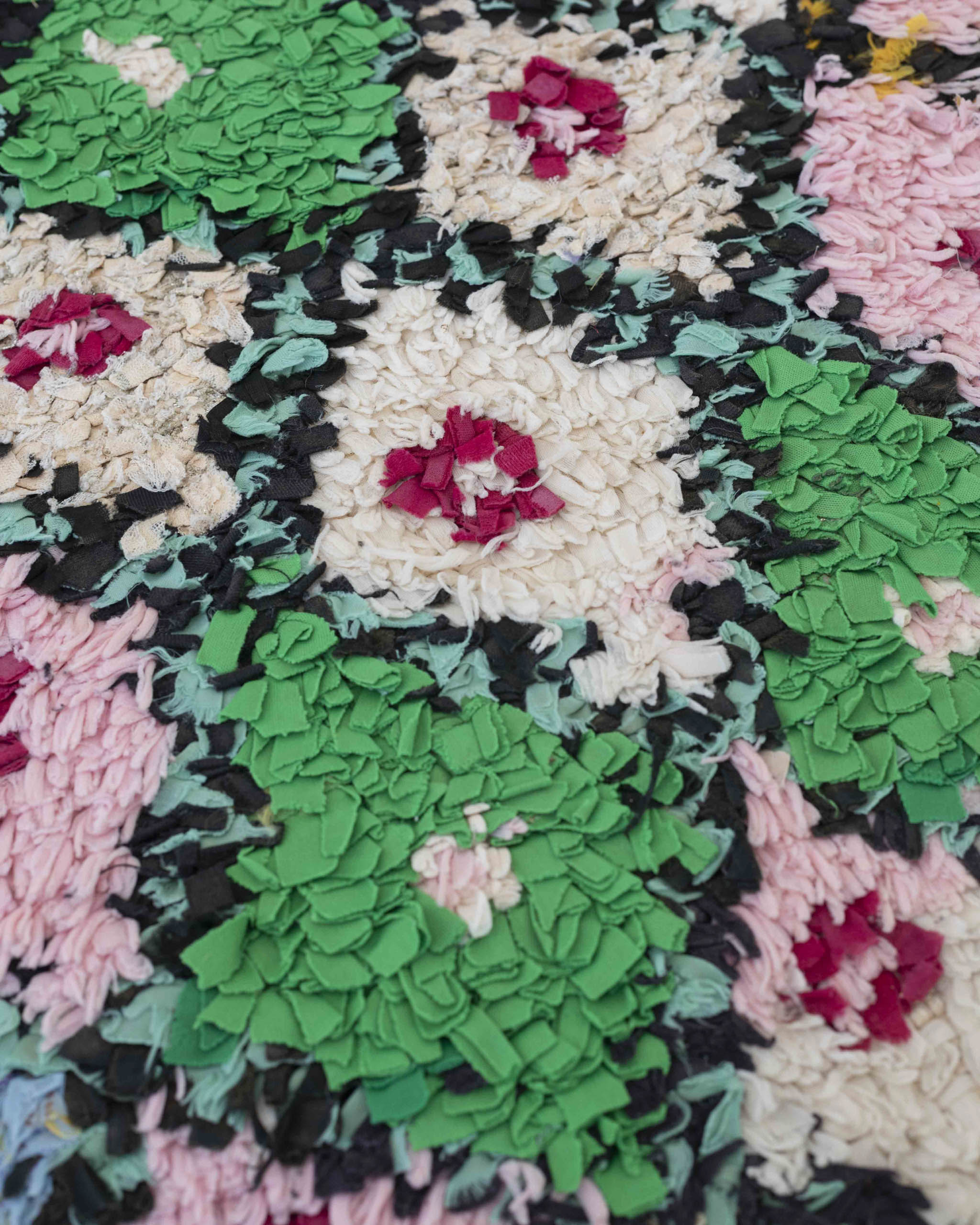 Dettaglio del tappeto boucherouite a rombi multicolore a frange di stoffe riciclate rosa, verdi, bianchi, rossi