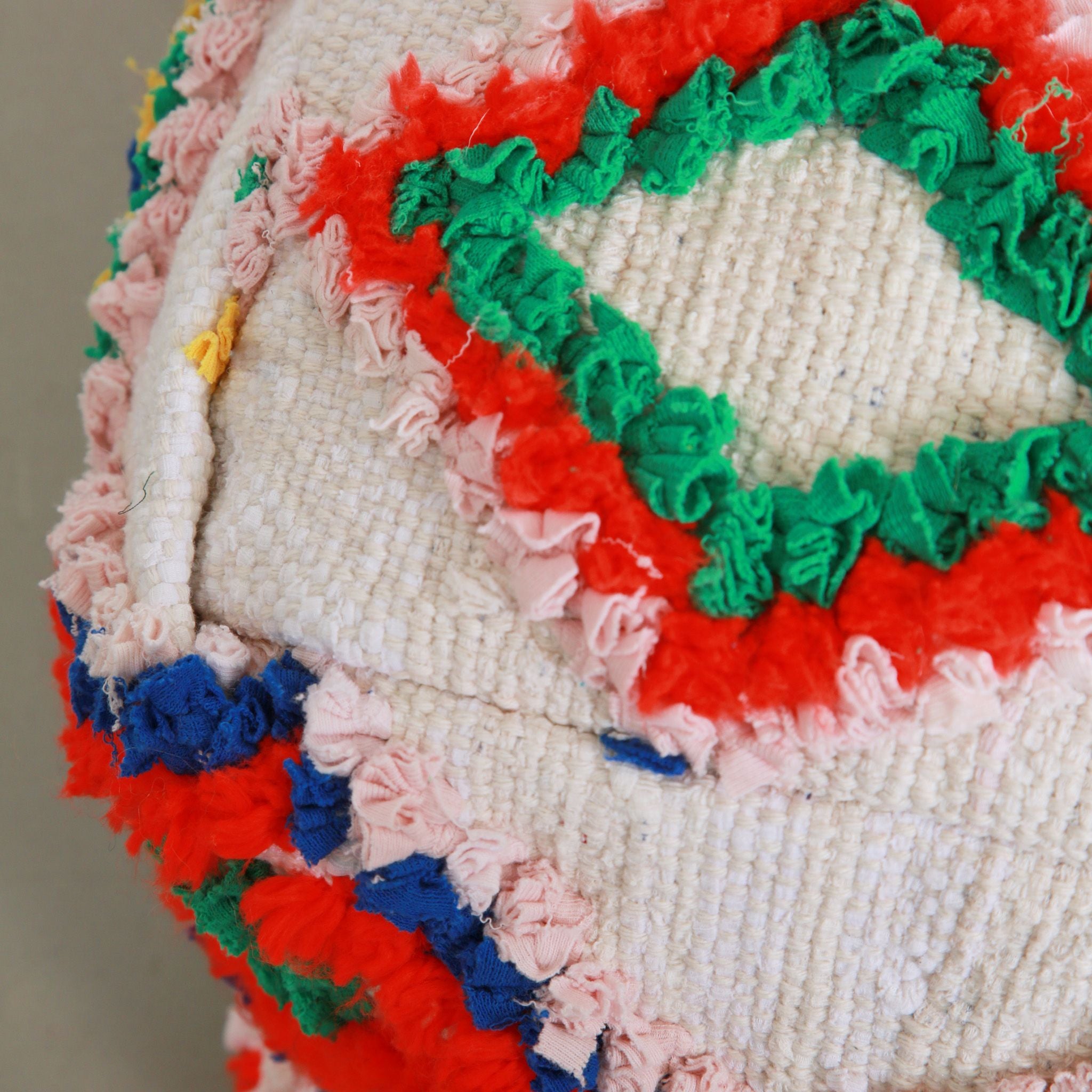 Dettaglio tessuto Boucherouite del pouf marocchino con rombi colorati in verde, rosso e rosa su base bianca