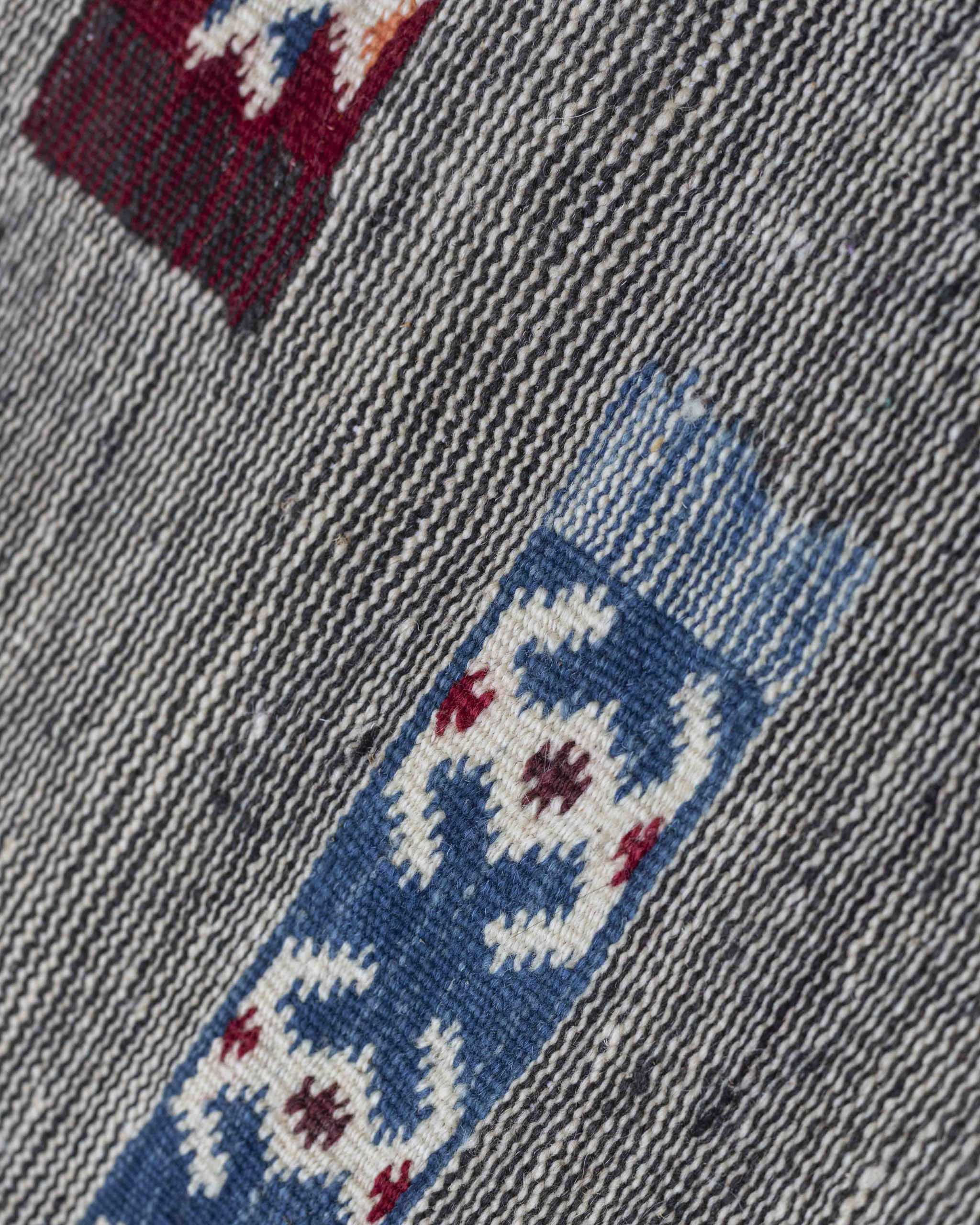 Dettaglio del tappeto in lana piatta bianco e nero con motivi geometrici colorati sparsi