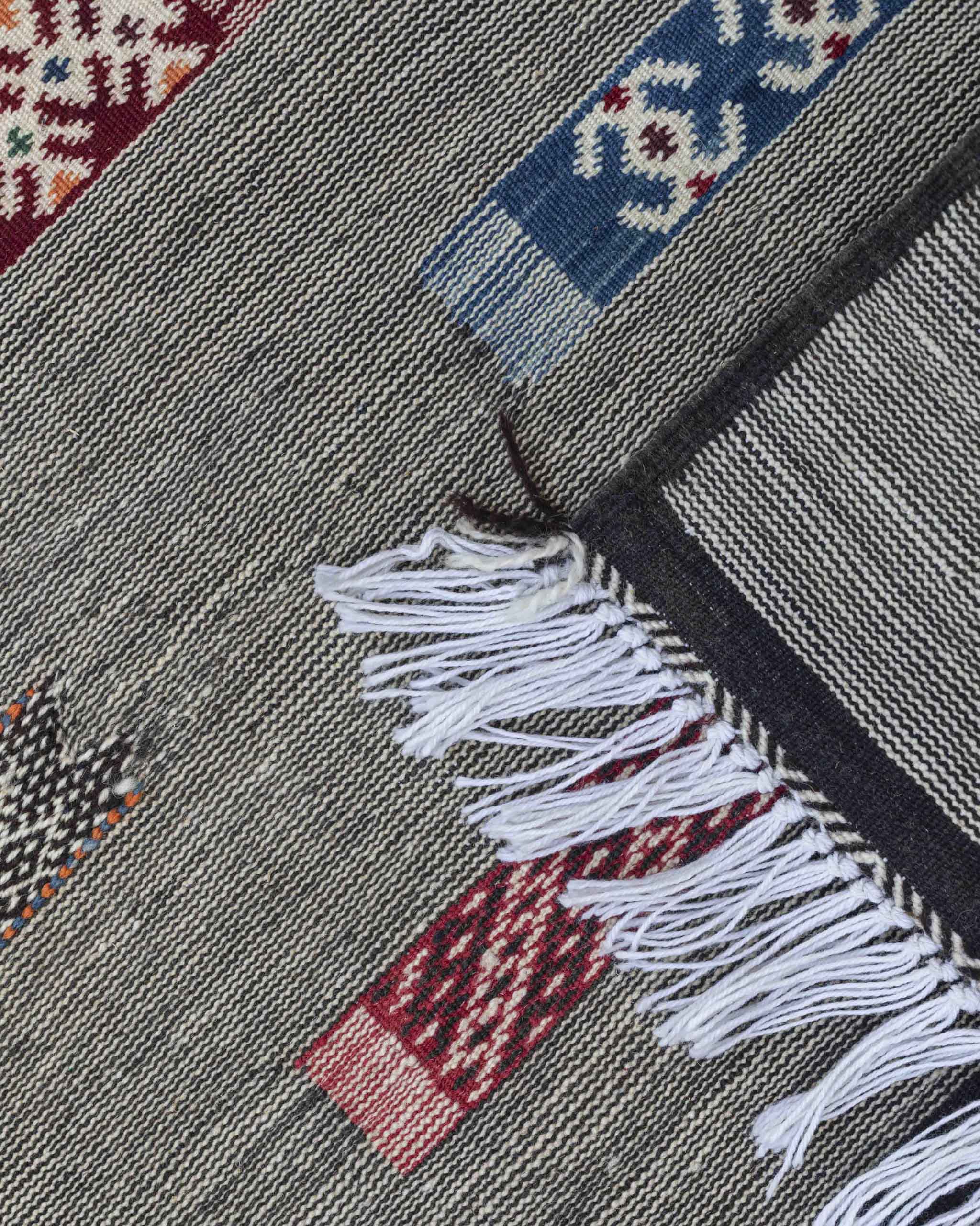 Dettaglio del tappeto a sottilissime righe nere e bianche con decori rettangolari colorati