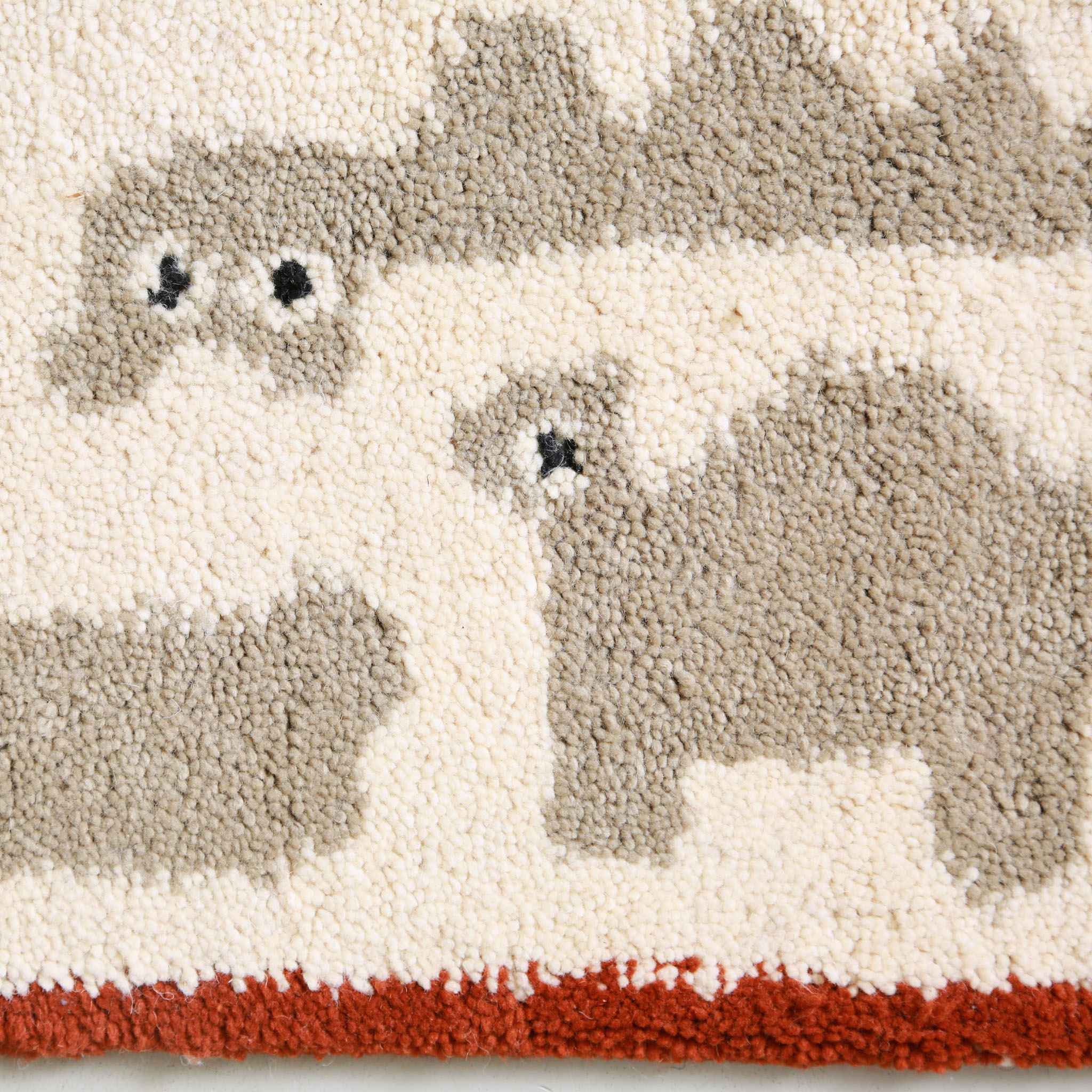 Dettaglio ravvicinato texture lana naturale con motivi animali creati da Oi mini design,  su tappeto fatto a mano