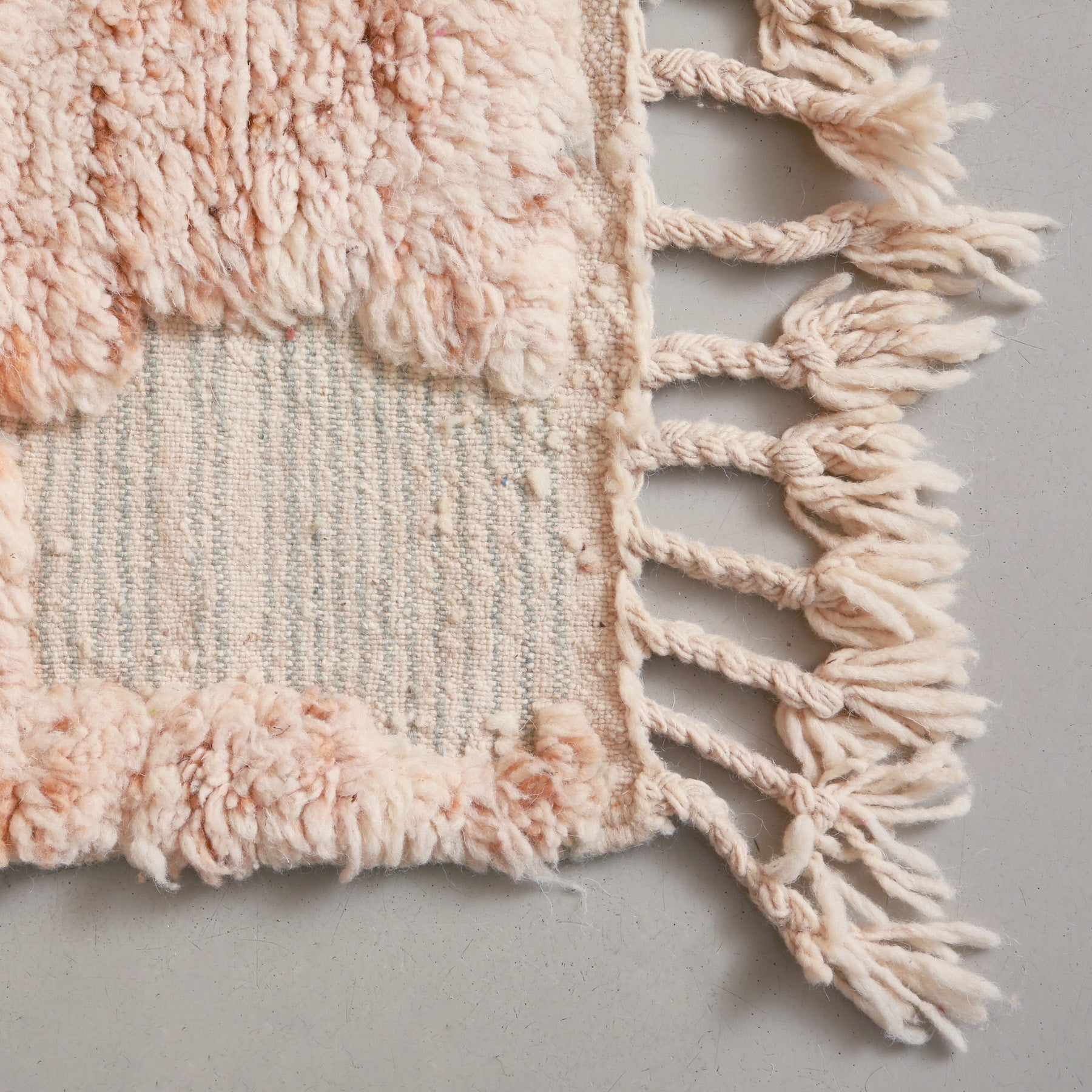 angolo di una passatoia beni ourain con frangia bianca e lana intrecciata e annodata chiara 