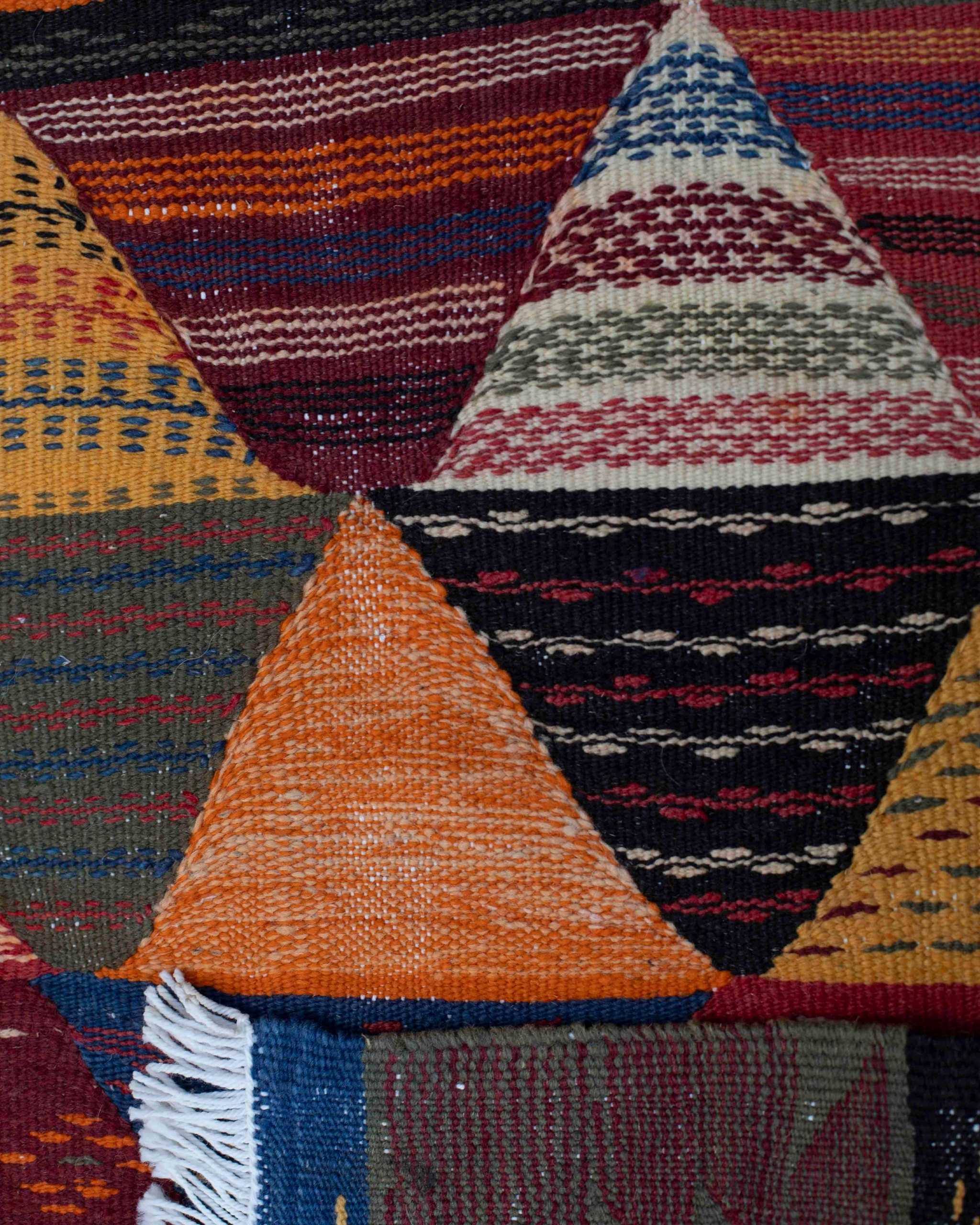 Dettaglio motivo a triangoli della passatoia Kharita: triangoli con micro-disegni in bordeaux, blu, verde, arancione, nero e avorio