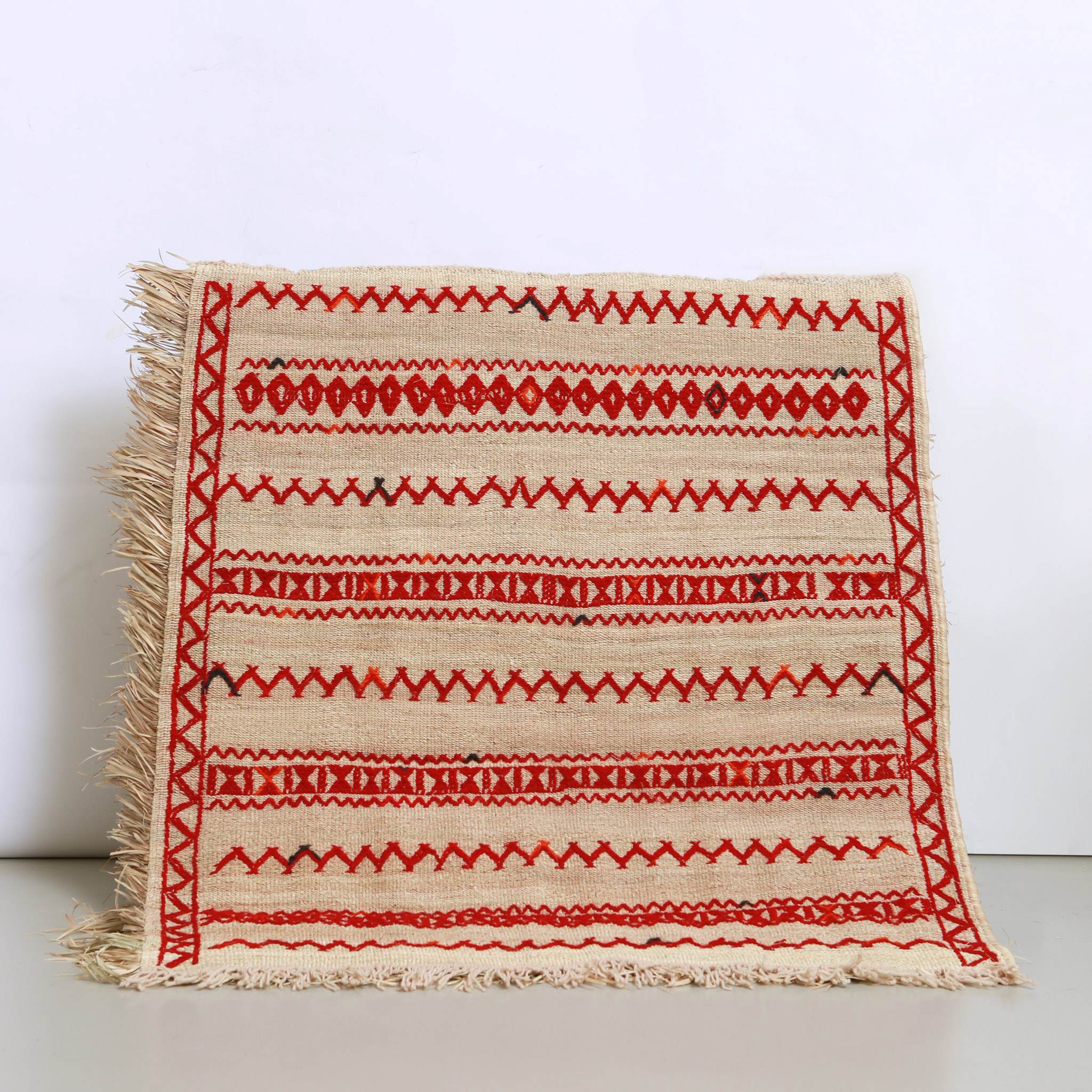 stuoia in paglia di palma realizzata artigianalmente in marocco con ricami a zig zag e geometrici in lana rossa