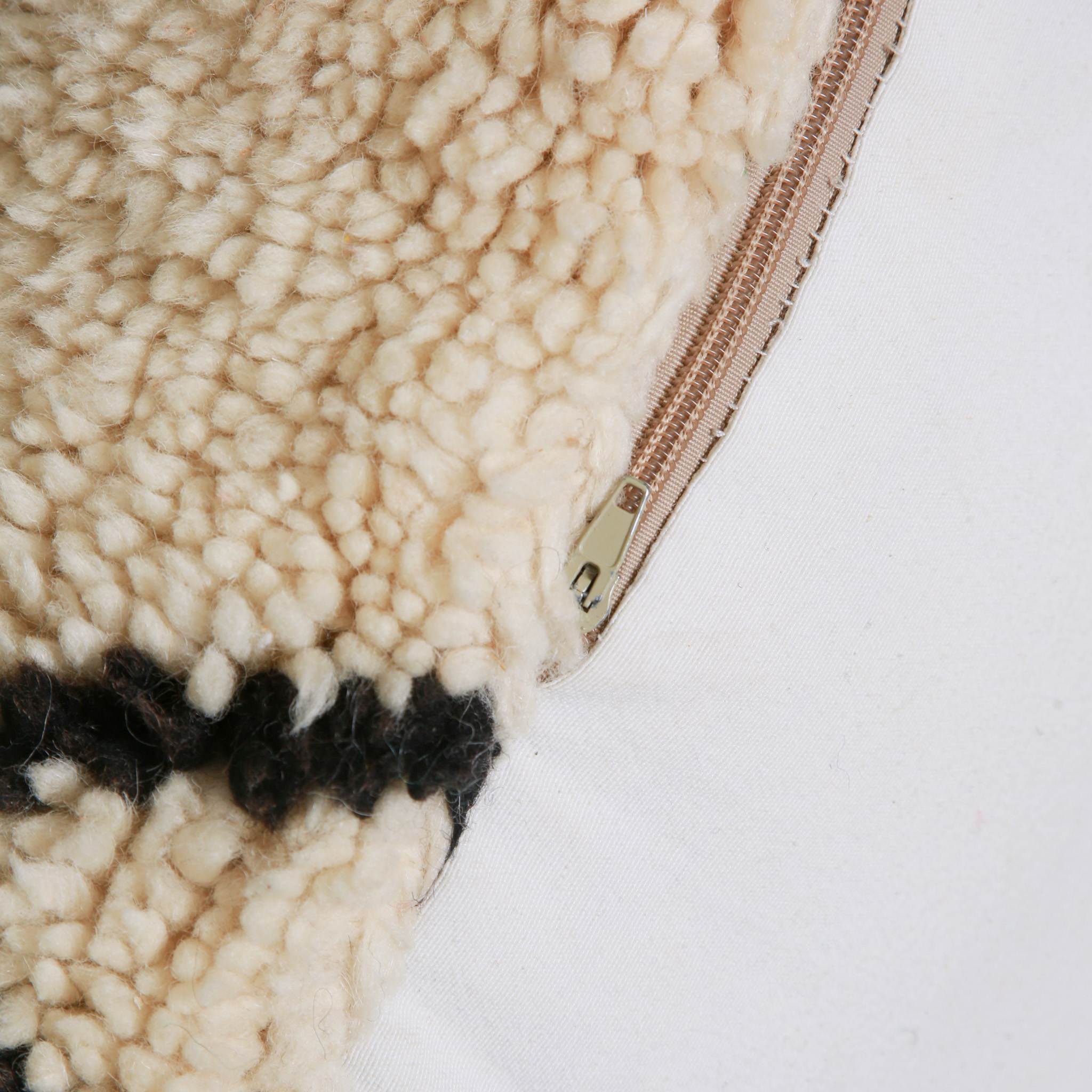 Dettaglio chiusura zip e texture lana a pelo alto del pouf berbero artigianale, cuscino da pavimento marocchino con finitura artigianale