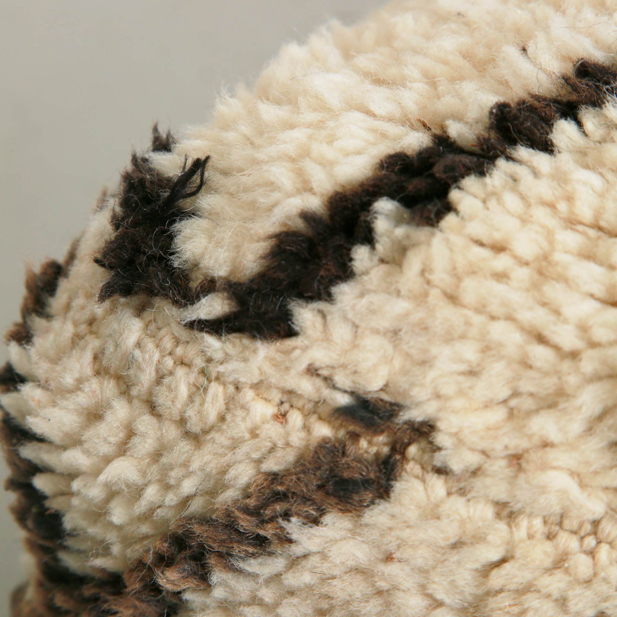 Close-up del pattern geometrico e lavorazione artigianale a mano del pouf marocchino in lana vergine, seduta stile berbero