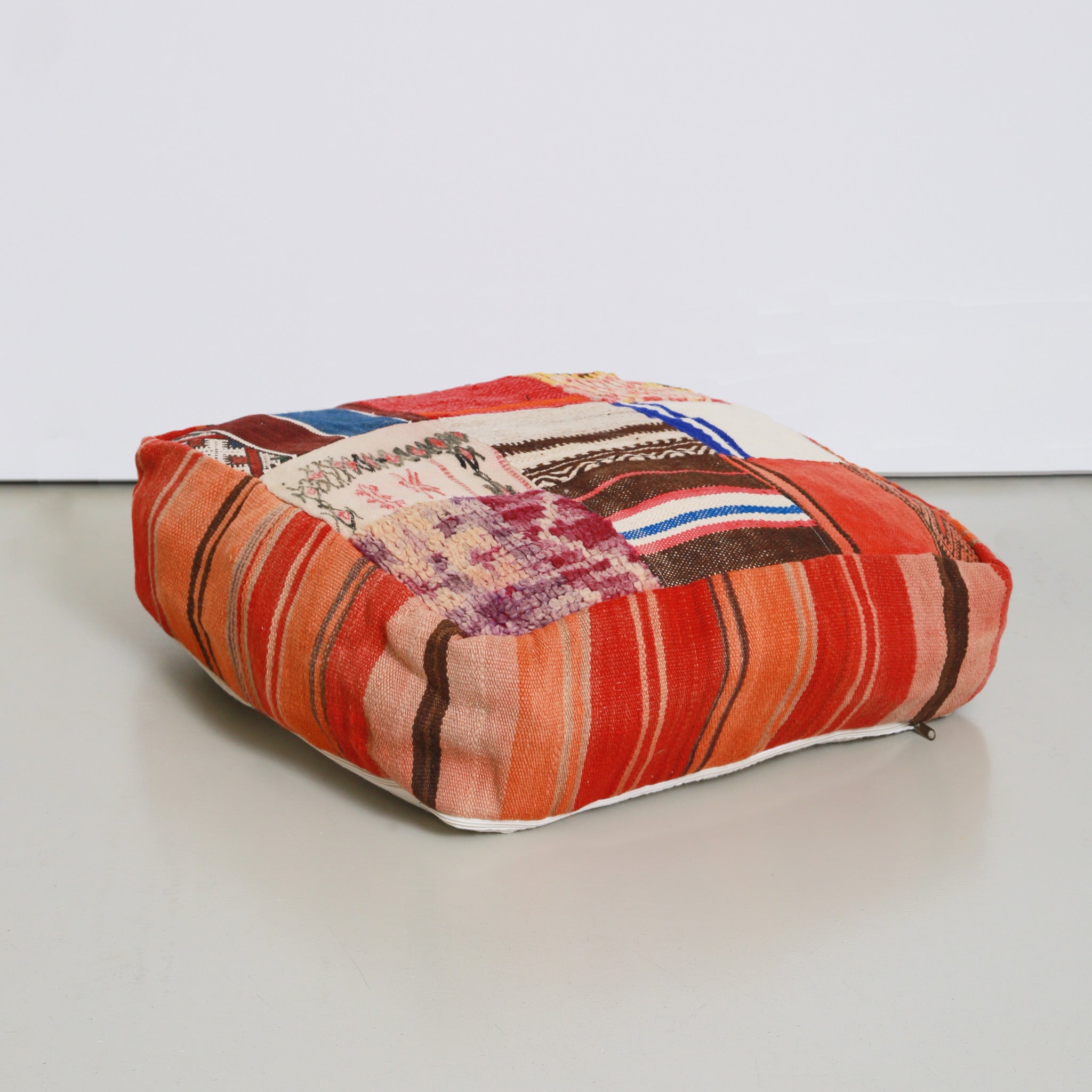 Pouf marocchino patchwork artigianale in tessuti riciclati con tonalità corallo, rosso e viola, realizzato a mano da artigiane del Marocco