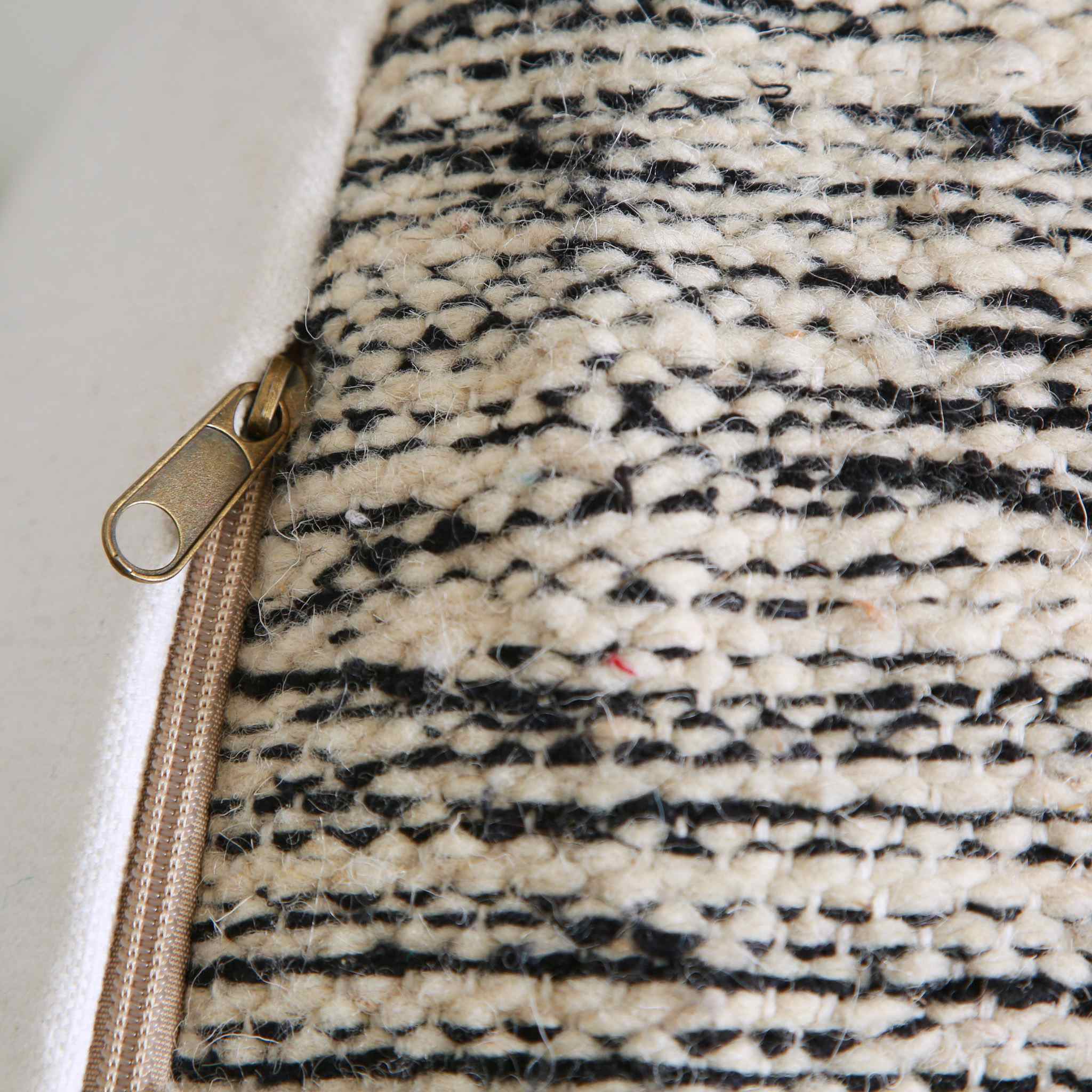 Dettaglio laterale pouf marocchino artigianale con tessuto geometrico bianco nero e chiusura zip dorata