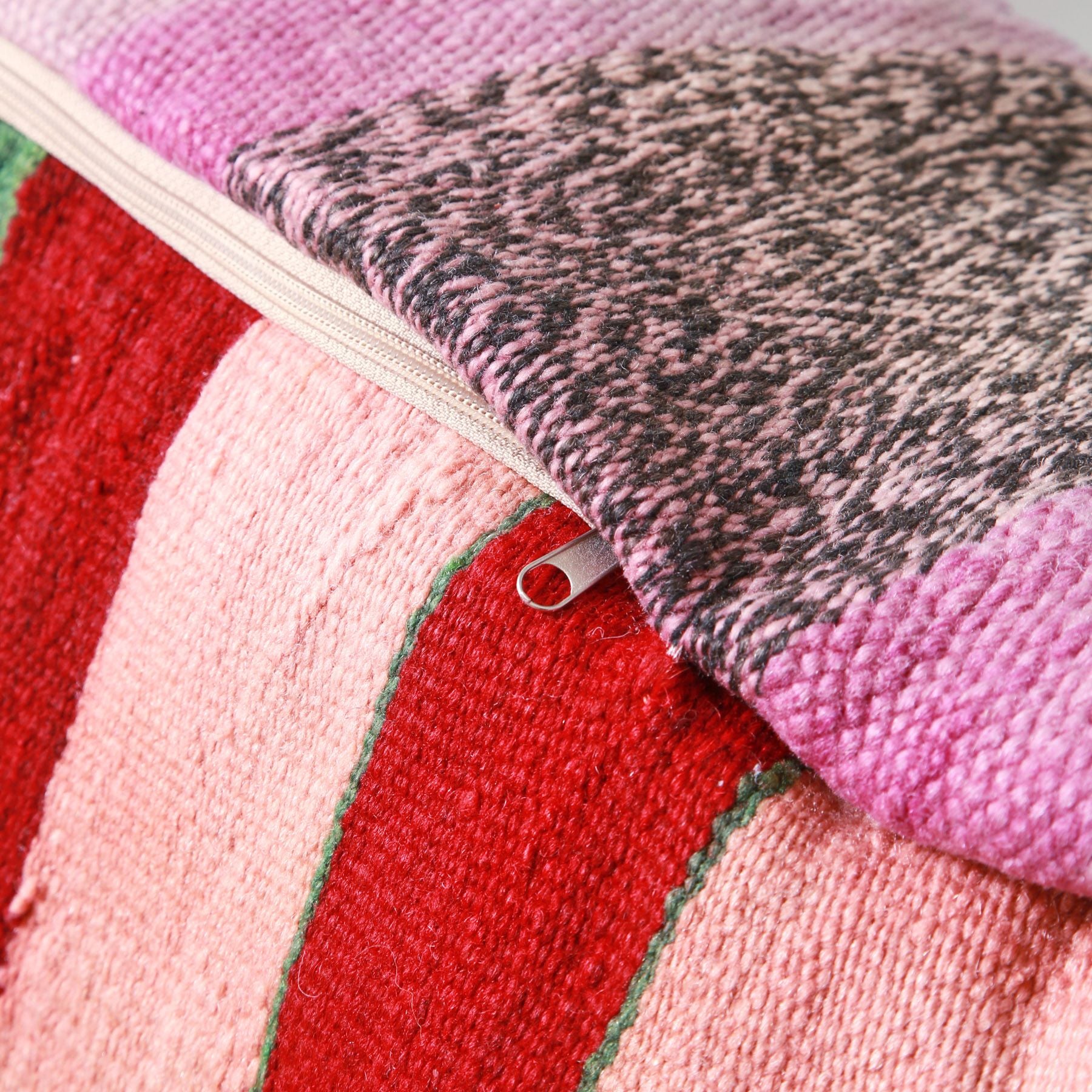 retro di un pouf che mostra la cerniera la base ricavata da una vecchia coperta marocchina a righe rosa e rosse e sopra un vecchio tappeto rosa e lilla